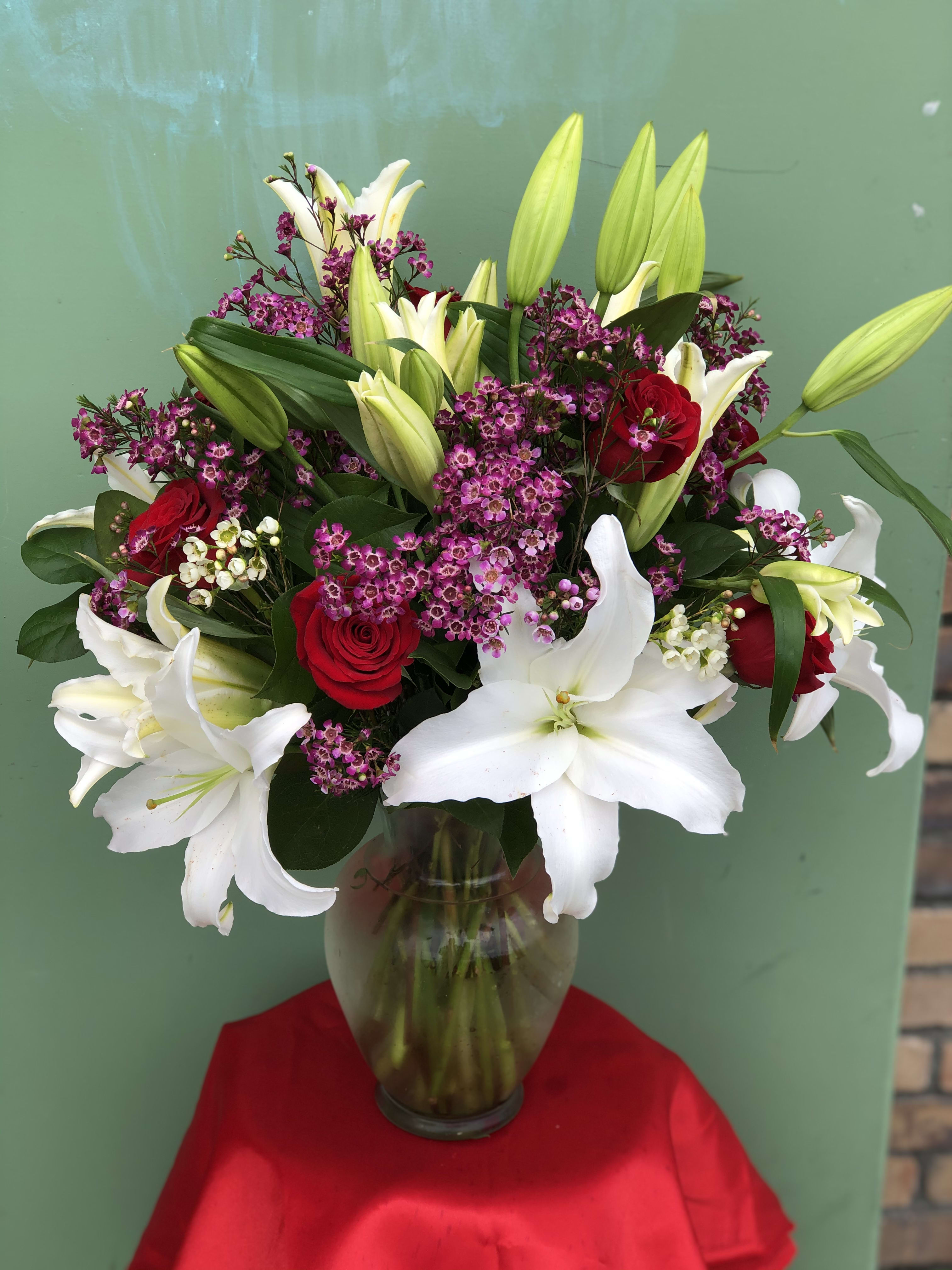 Bouquet of white lilies and red roses in a glass vase