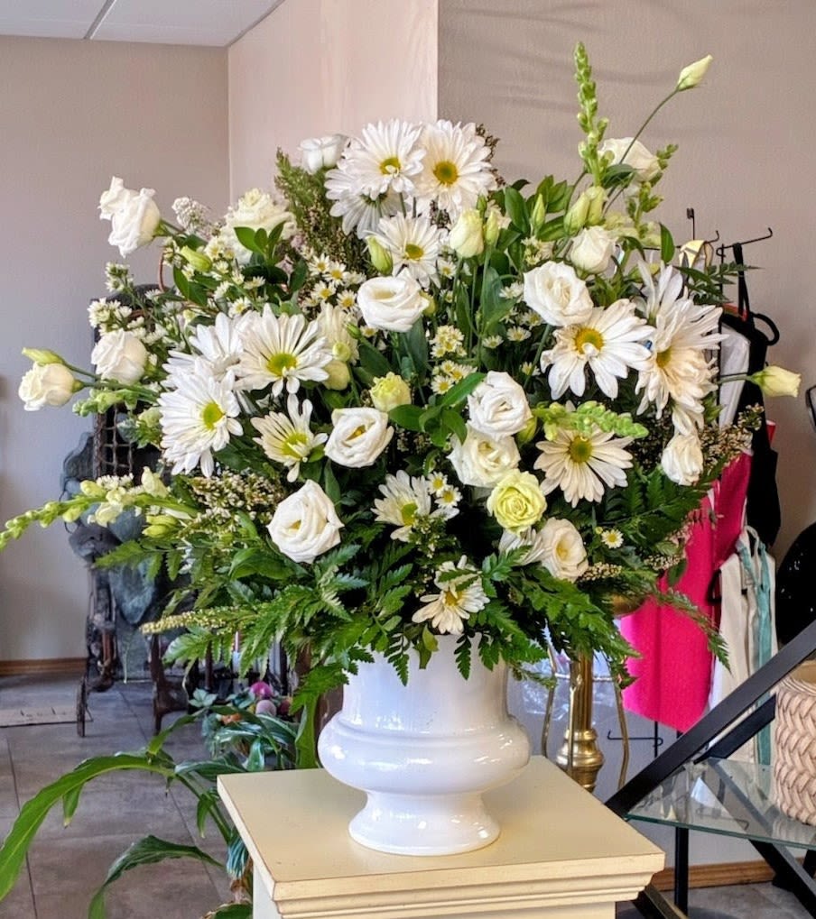 Large white floral arrangement in a white urn vase