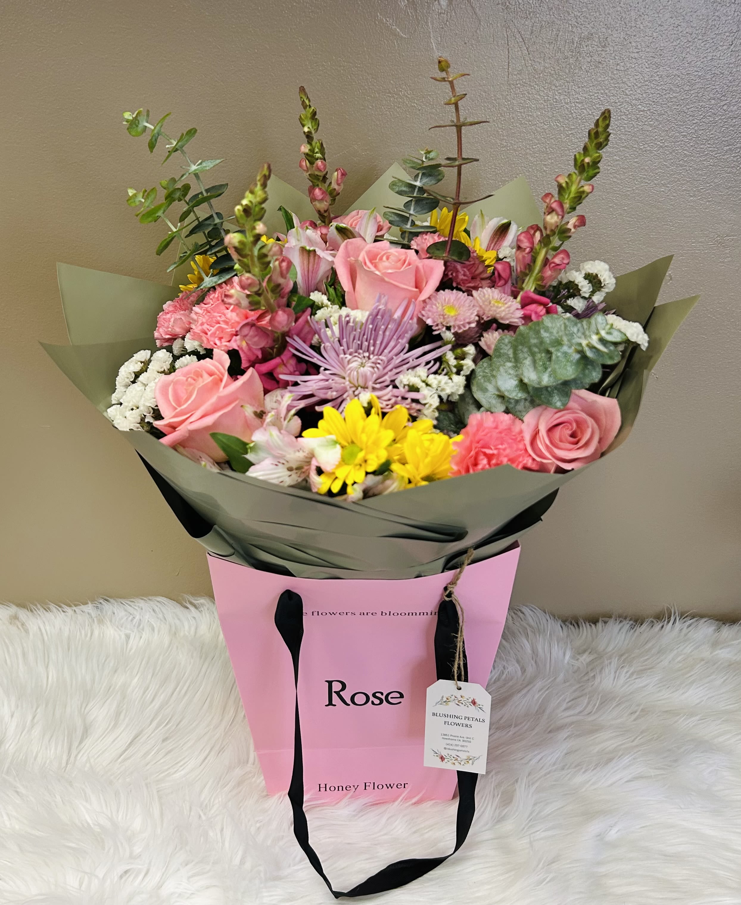 Bouquet of pink roses, yellow daisies, and mixed blooms in pink wrapping