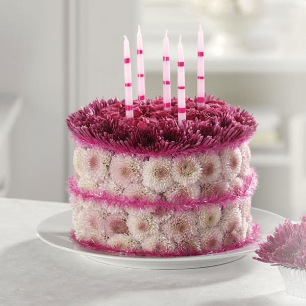Round floral cake with pink and white flowers and striped candles