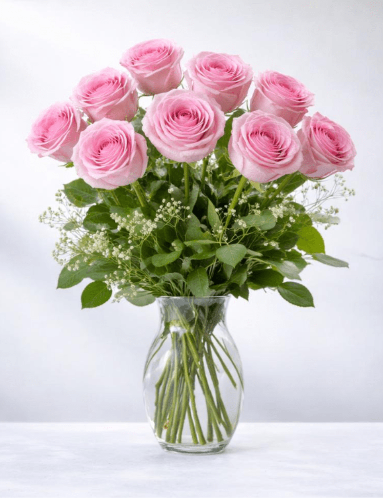 Arrangement of pink roses with white filler flowers in a clear glass vase