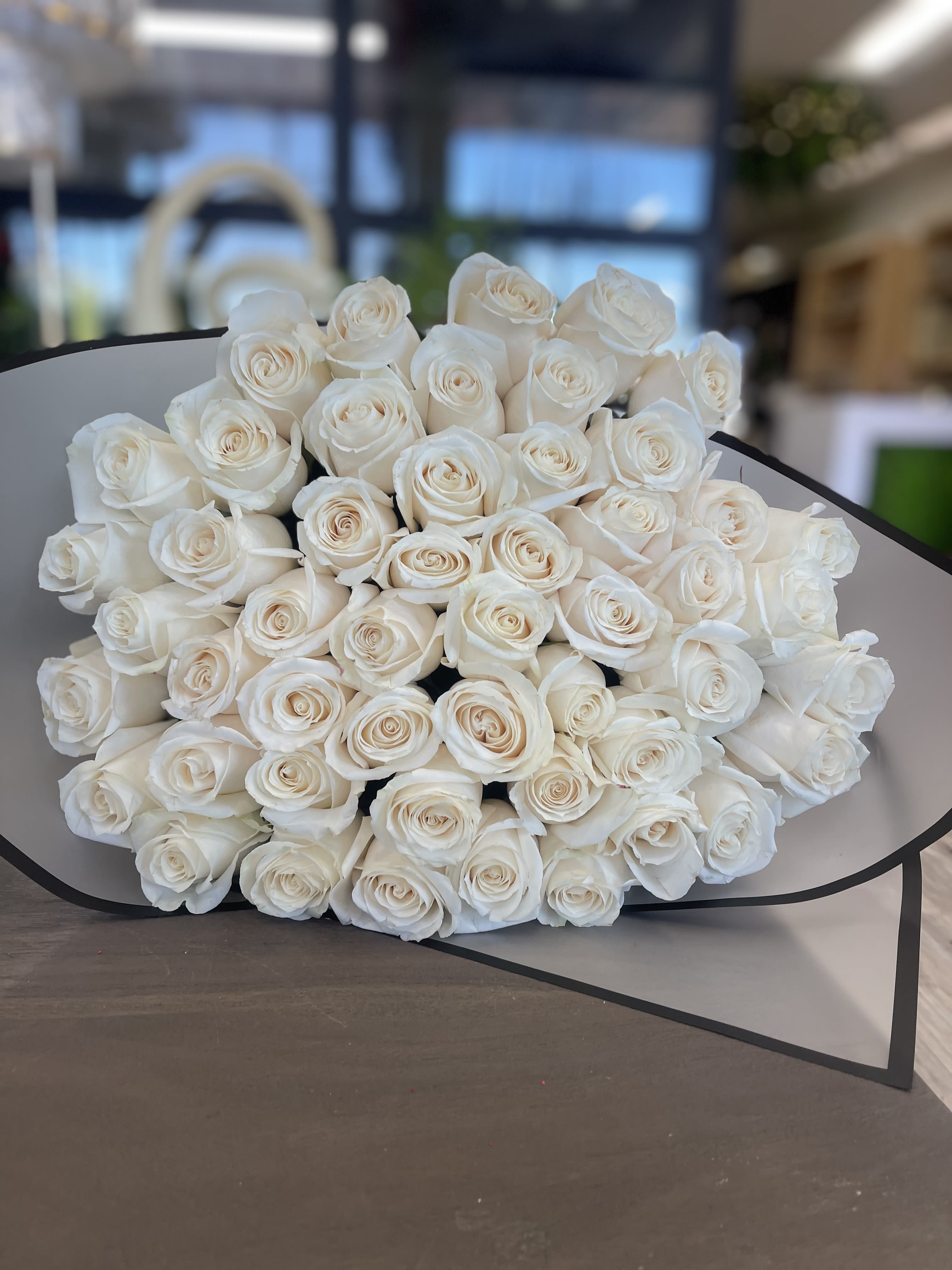 Large bouquet of white roses wrapped in gray paper