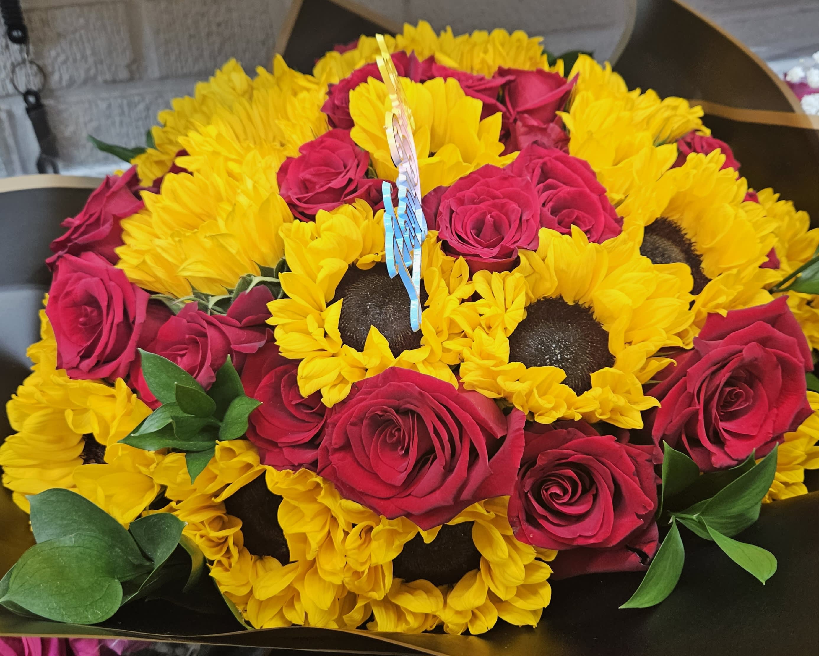 Bouquet of yellow sunflowers and hot pink roses in dark wrapping