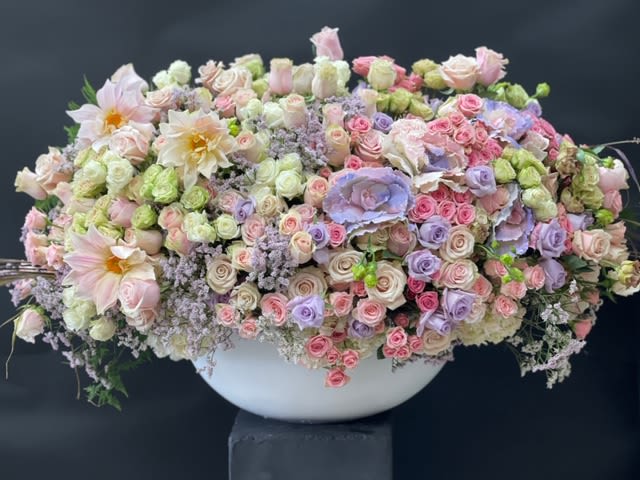 Large pastel floral arrangement in a white bowl vase