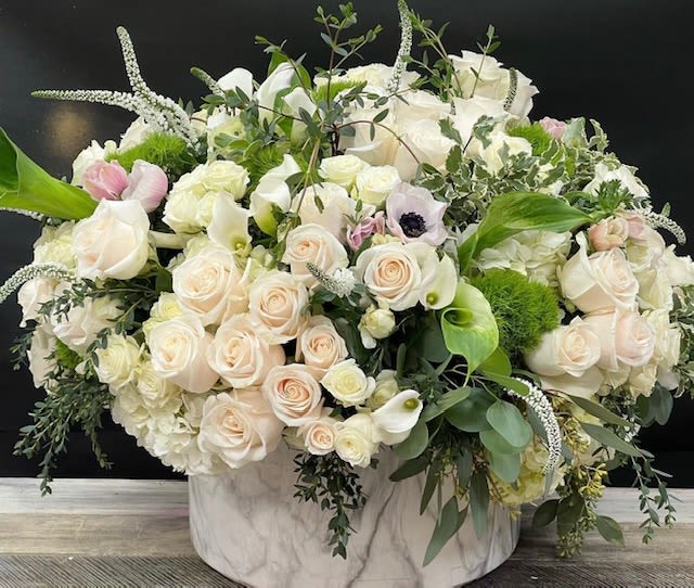 Large white and blush rose arrangement in a marble-patterned vase