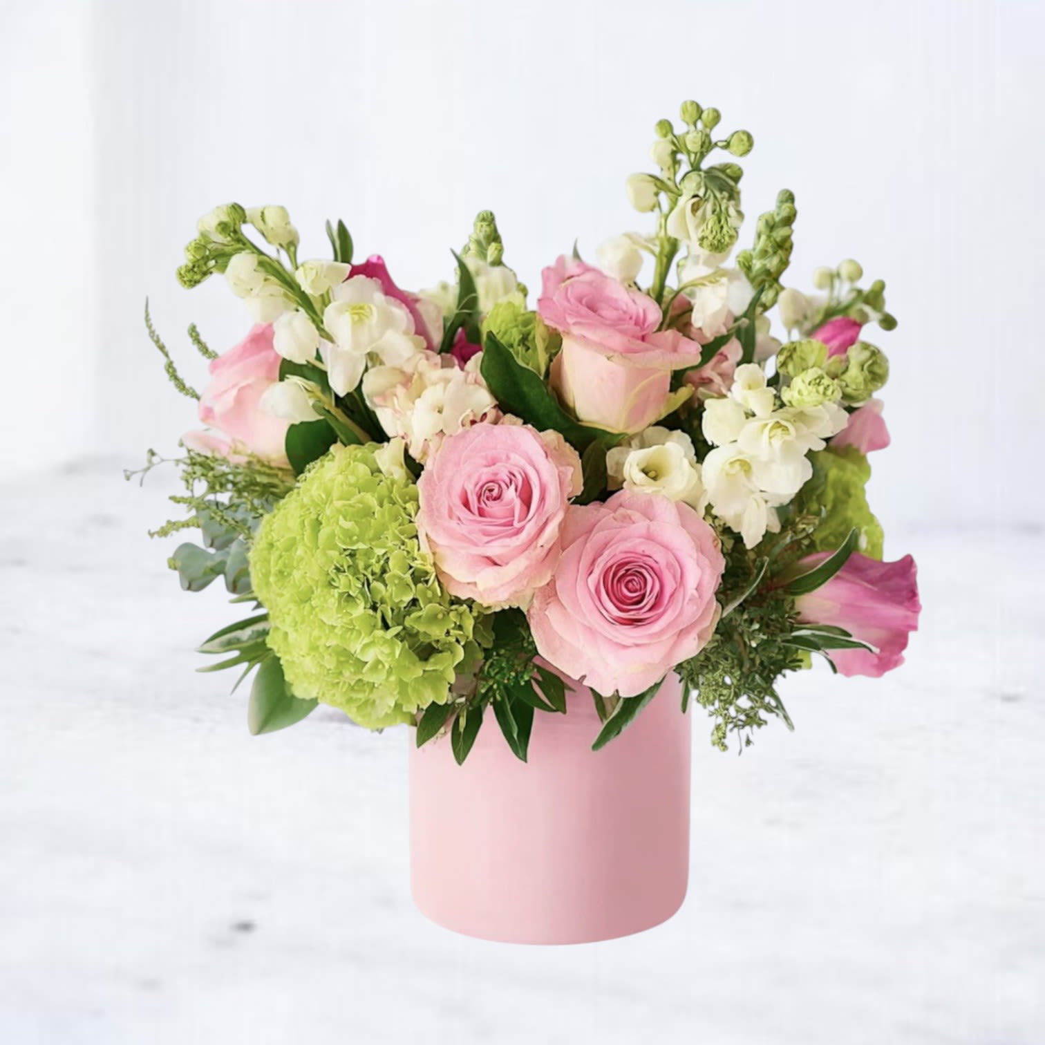 Pink Reverie - Fresh, feminine, and effortlessly charming, Pink Reverie is a soft garden-style arrangement designed to brighten any occasion. Featuring blush pink roses, delicate stock, lush green hydrangea, and seasonal accent blooms, this arrangement blends airy texture with a clean, modern palette for a look that feels both elegant and uplifting.  Designed in a soft pink ceramic vase, Pink Reverie is perfect for birthdays, baby showers, thank-you gifts, get-well wishes, anniversaries, or simply adding a touch of beauty to everyday moments. Its light, cheerful color palette makes it a timeless favorite for year-round gifting.  Available for same-day flower delivery in Galveston, Jamaica Beach, Tiki Island, Sea Isle, Hitchcock, La Marque, Texas City, Dickinson, League City, Kemah, Clear Lake, Webster, and surrounding coastal areas.