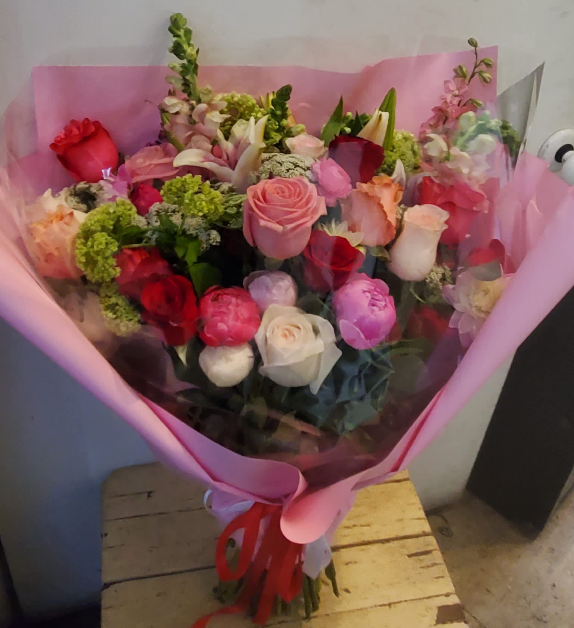 Bouquet of mixed roses and other flowers wrapped in pink paper