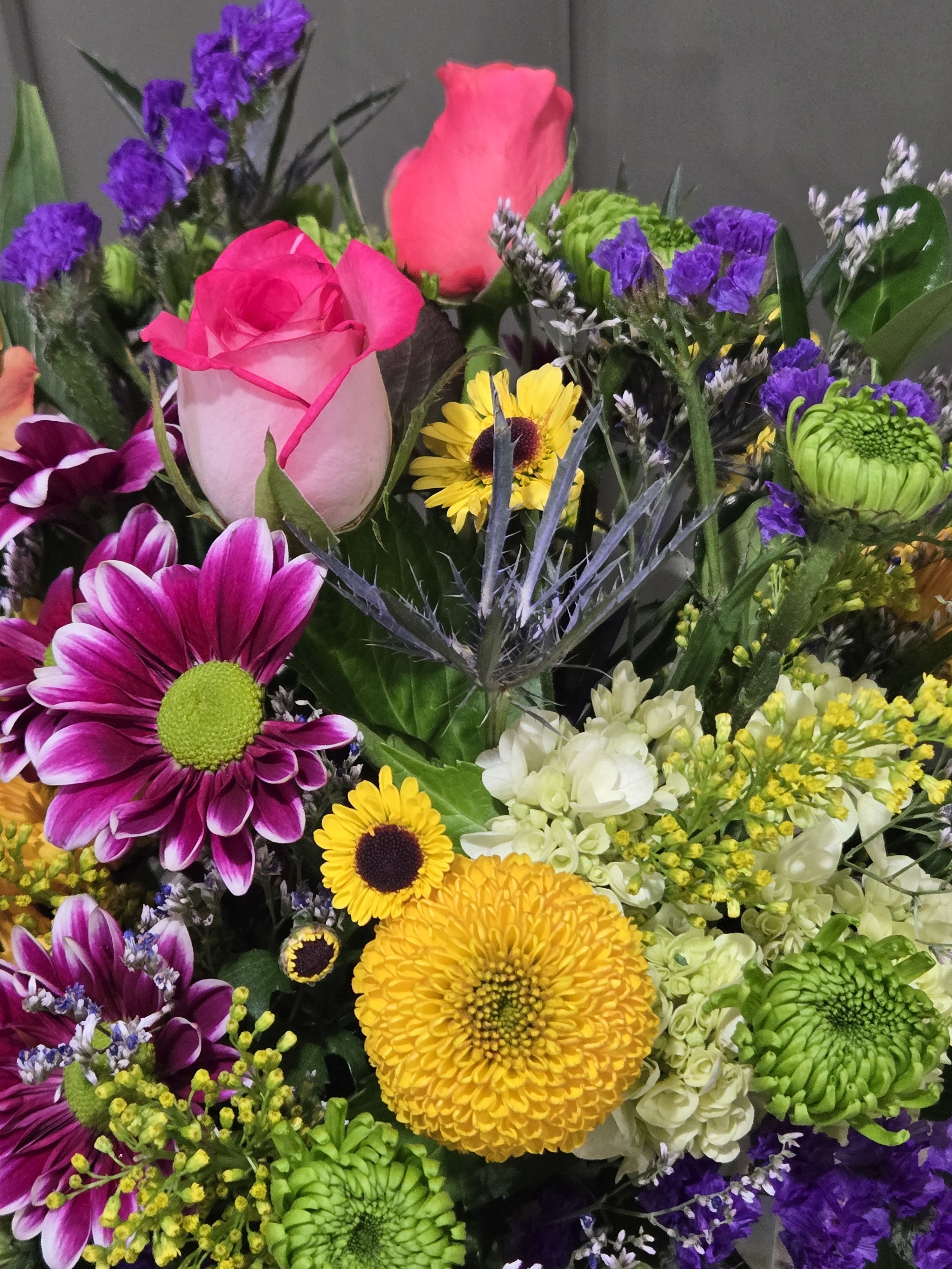 Bright mixed bouquet with pink roses, yellow and green chrysanthemums, and purple accents
