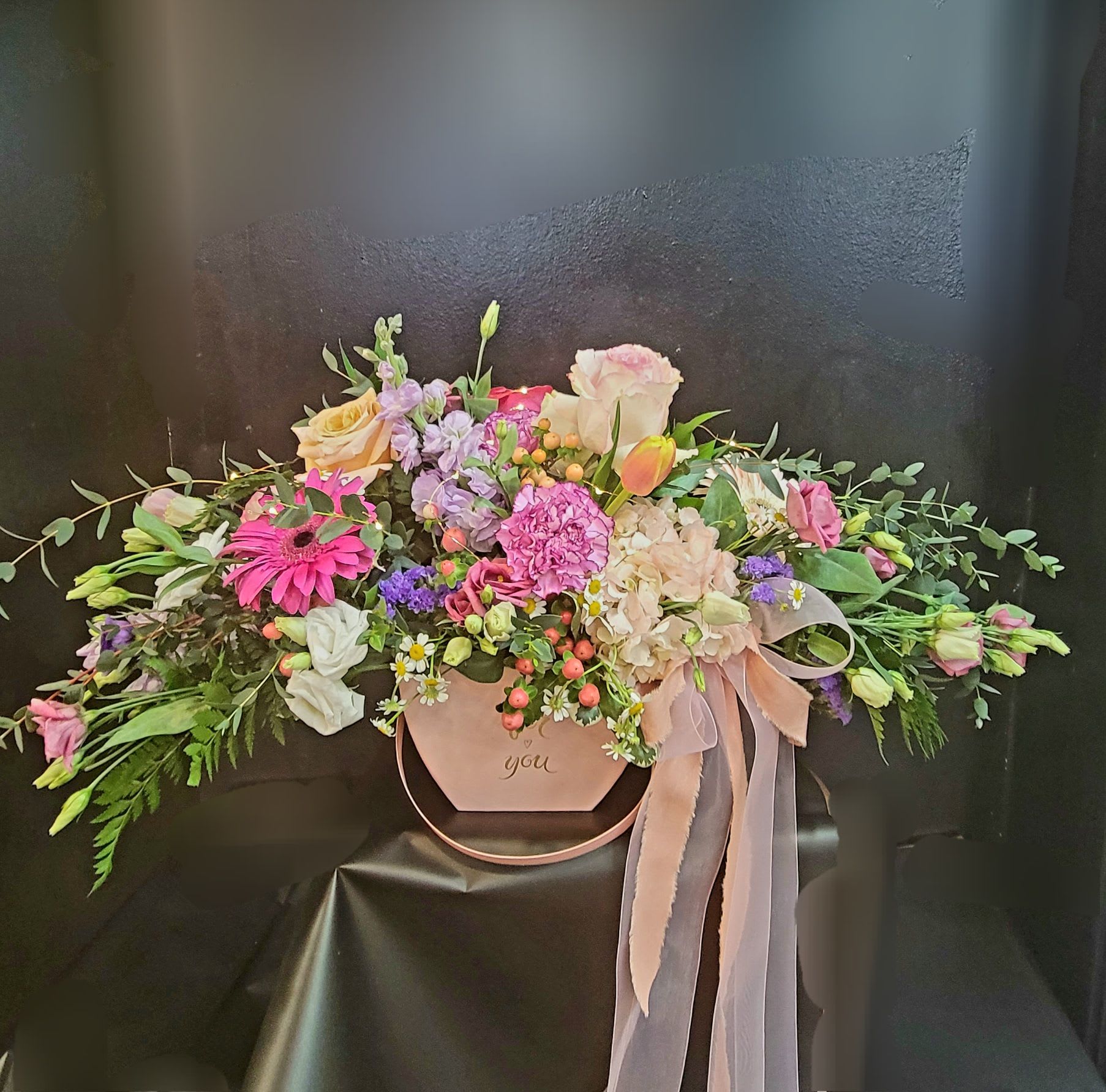 Pastel floral arrangement in a pink hat box with ribbon
