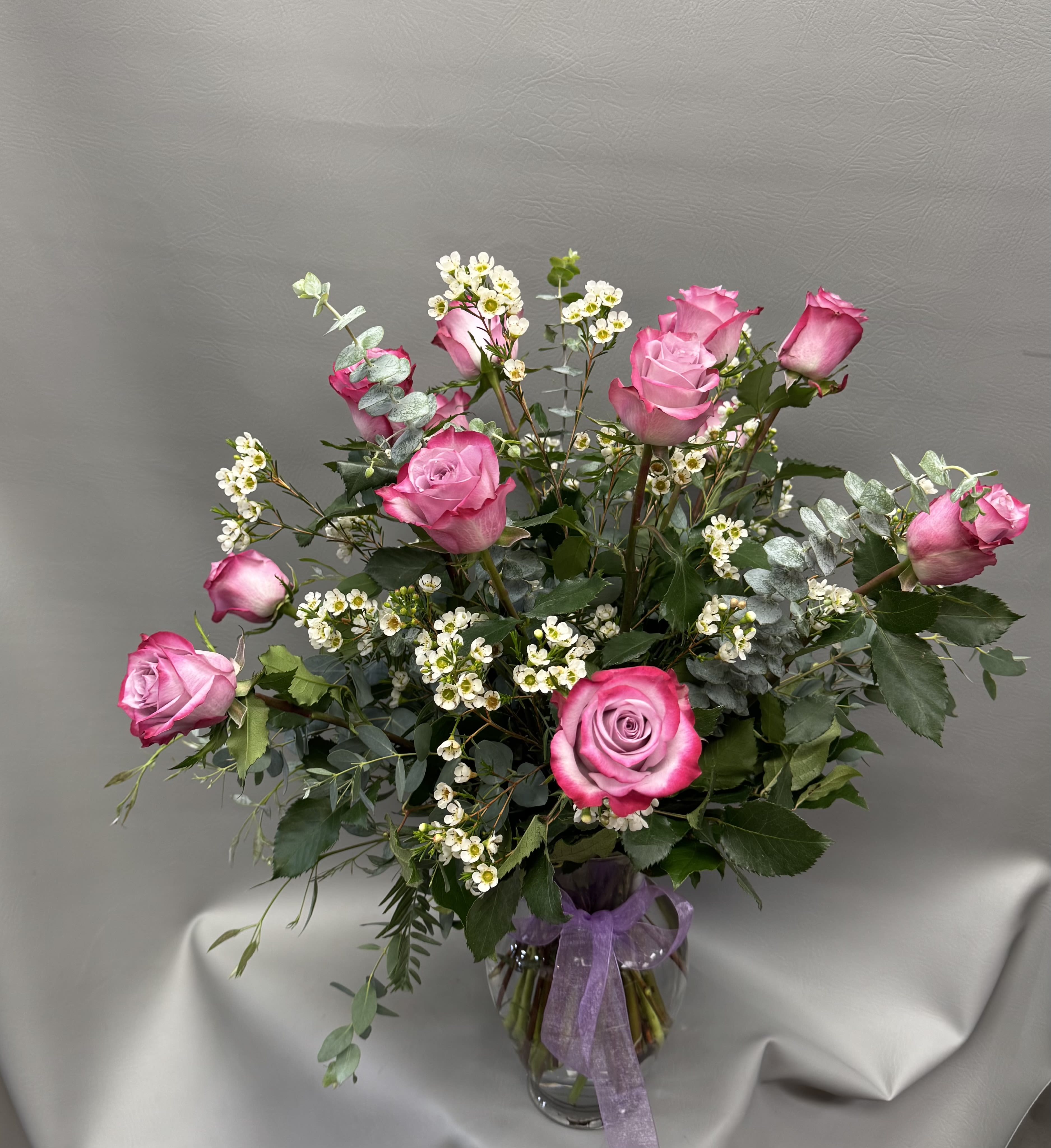 Pink roses arranged in a clear glass vase with small white filler flowers