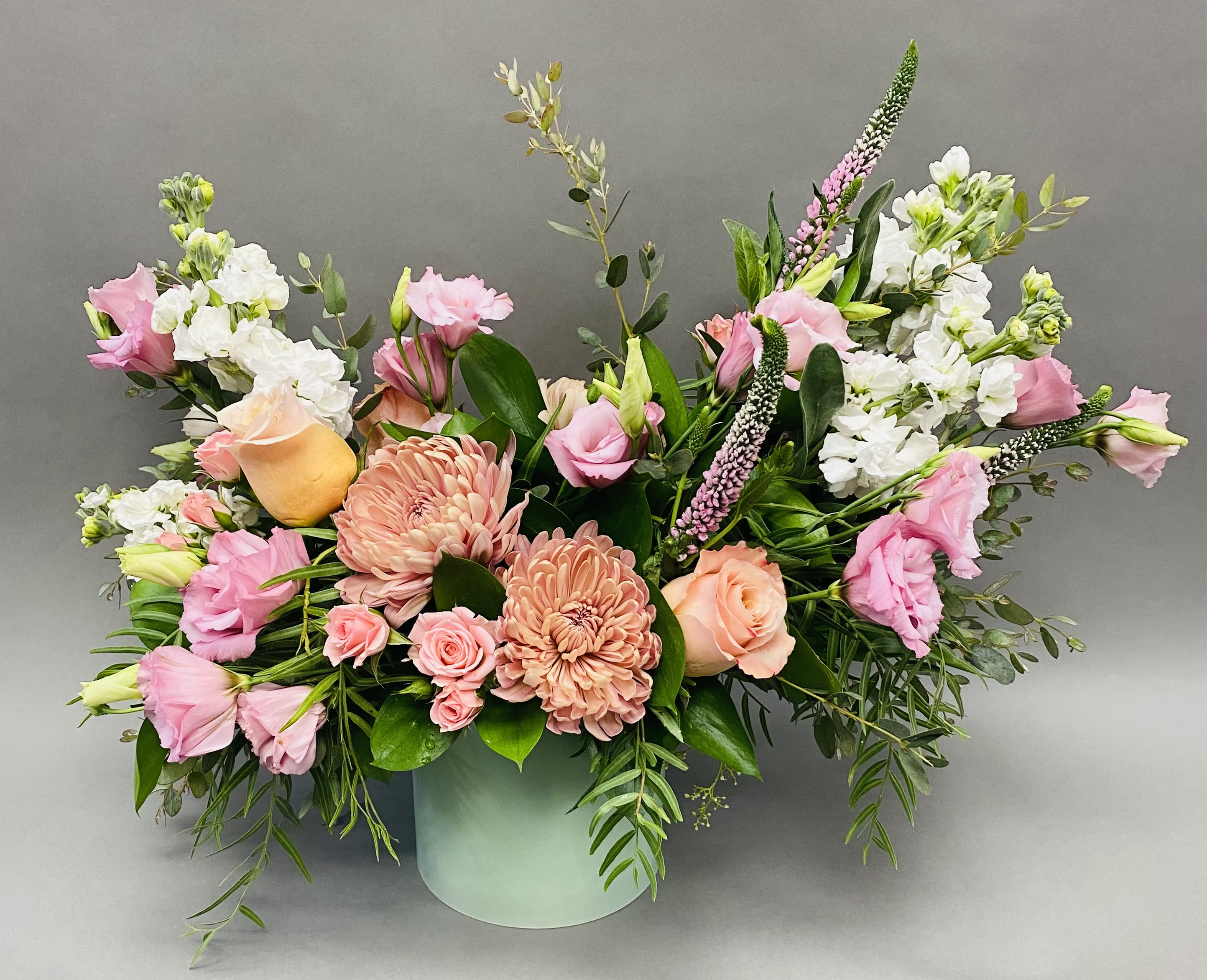 Pink and peach floral arrangement in a pale green vase