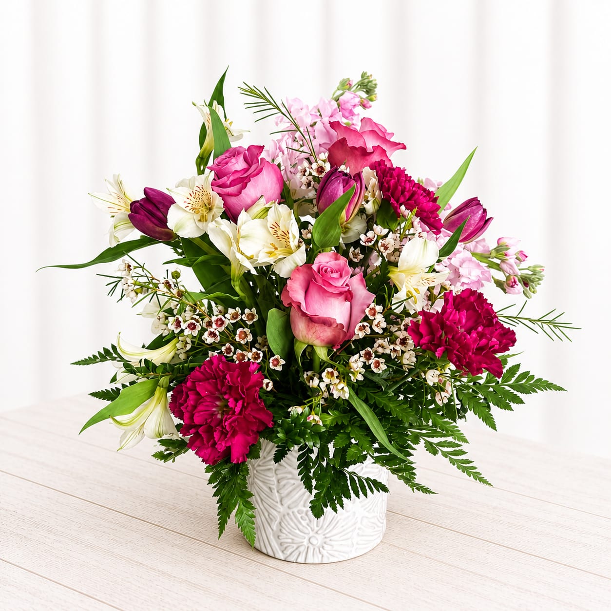 Berry Blush - Rich, romantic, and full of texture—Berry Blush Garden is a stunning mix of soft pink roses, deep berry-toned blooms, and delicate accents that create a lush, garden-inspired look. Designed in a textured white container, this arrangement blends elegance with a slightly wild, organic feel. Perfect for anniversaries, heartfelt moments, or when you want something a little deeper than your typical pinks.