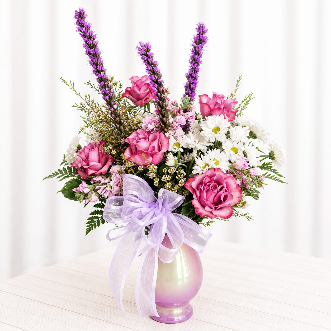 Sweet Wishes - Soft, sweet, and full of charm—Lavender Blush Delight is a dreamy mix of blush pink roses, delicate daisies, and airy lavender accents. Designed in a shimmering keepsake vase and finished with a soft ribbon, this arrangement has a whimsical, garden-picked feel with just the right touch of elegance. Perfect for birthdays, get well wishes, or sending a little happiness “just because.”