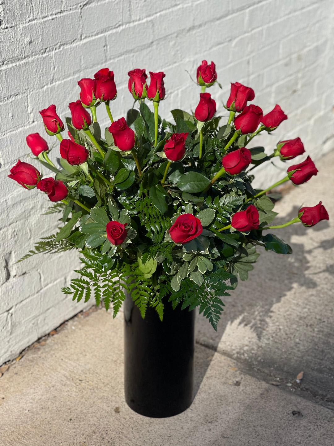 Red roses arranged in a tall black vase