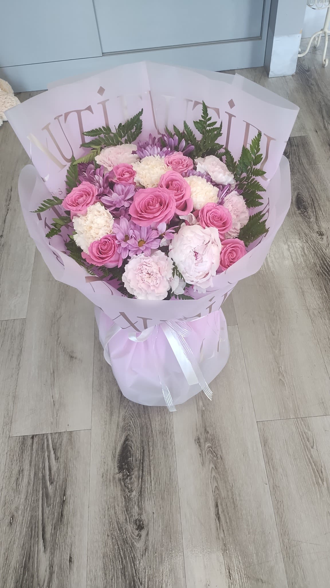 Pink and lavender bouquet with roses and carnations wrapped in pale paper