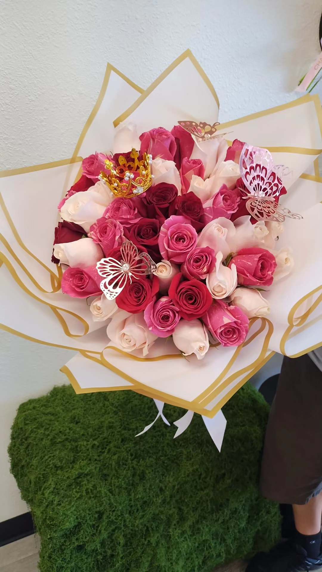 Bouquet of pink and white roses wrapped in white paper with gold trim