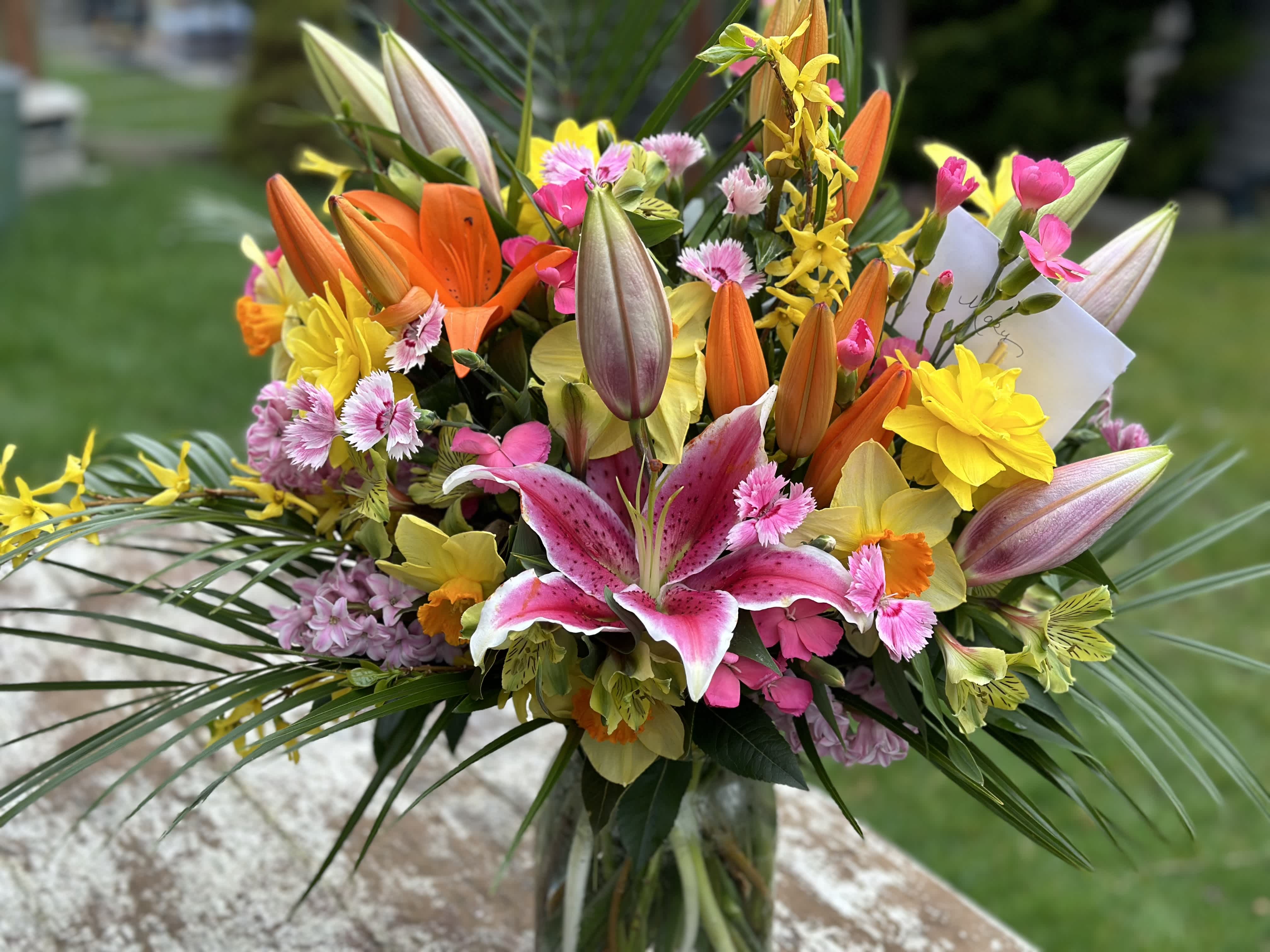 Colorful bouquet with lilies, daisies, and pink flowers in a glass vase