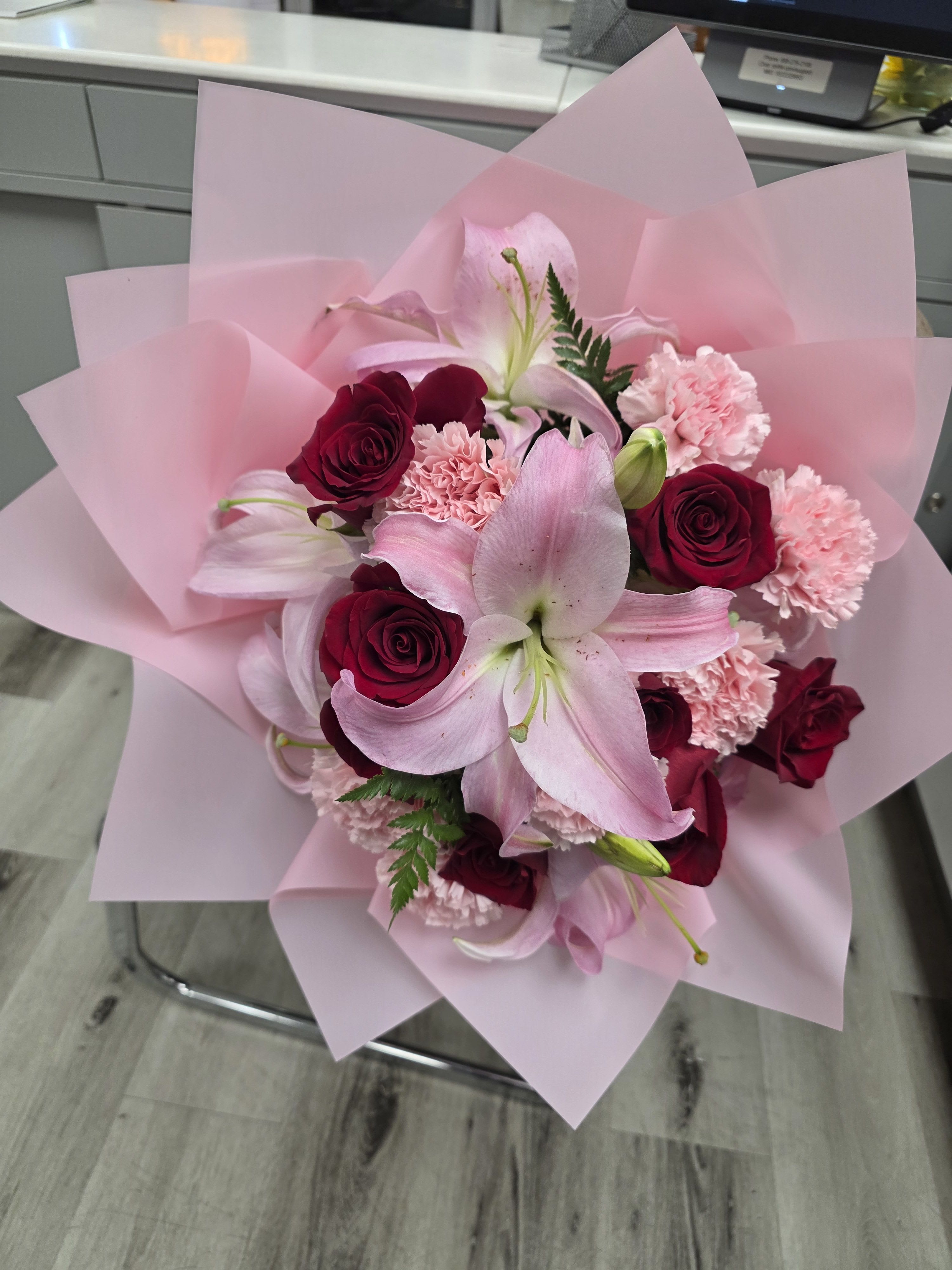 Pink lily and red rose bouquet wrapped in pale pink paper