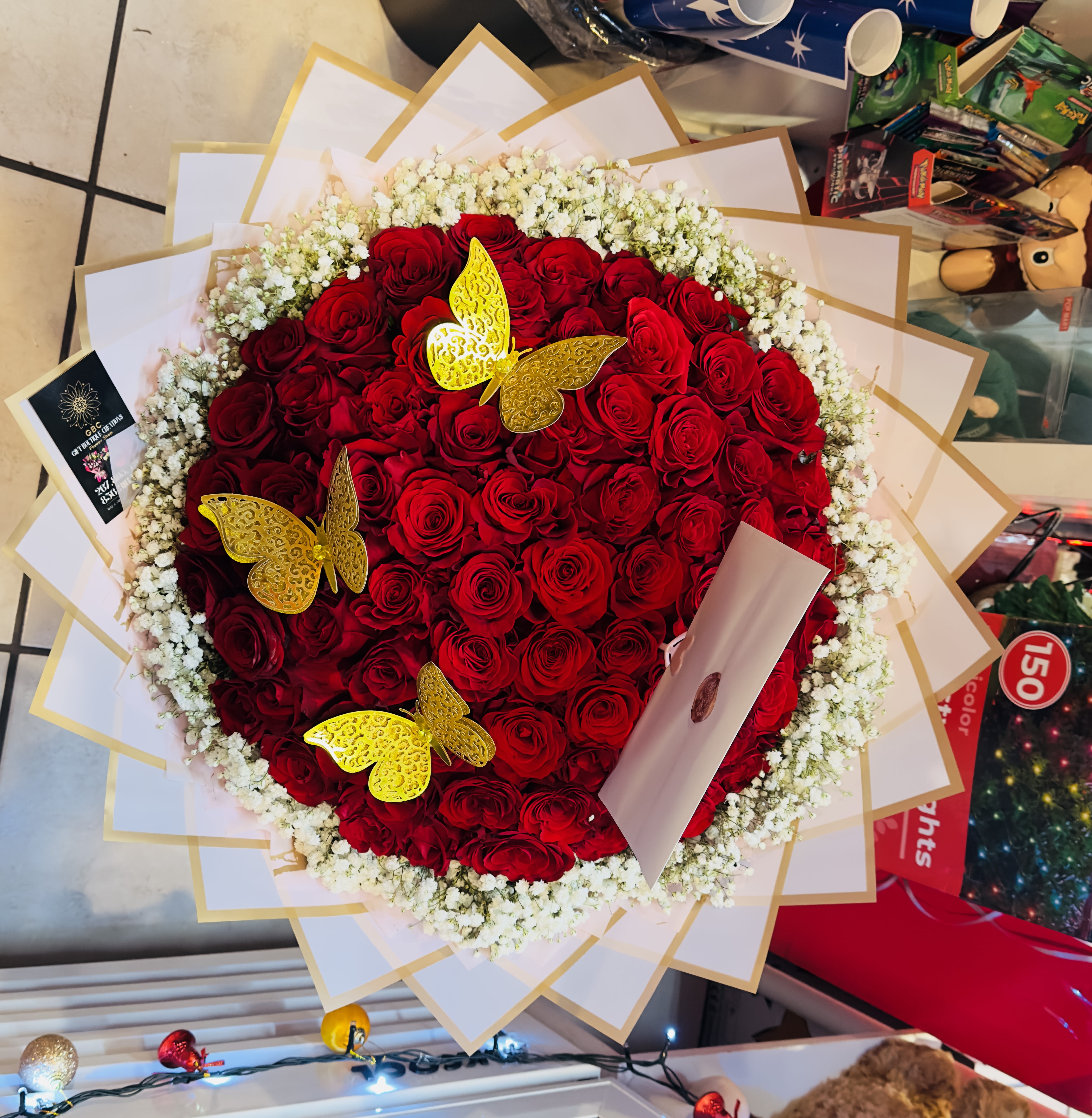 Heart-shaped bouquet of red roses with white baby's breath and gold butterfly accents