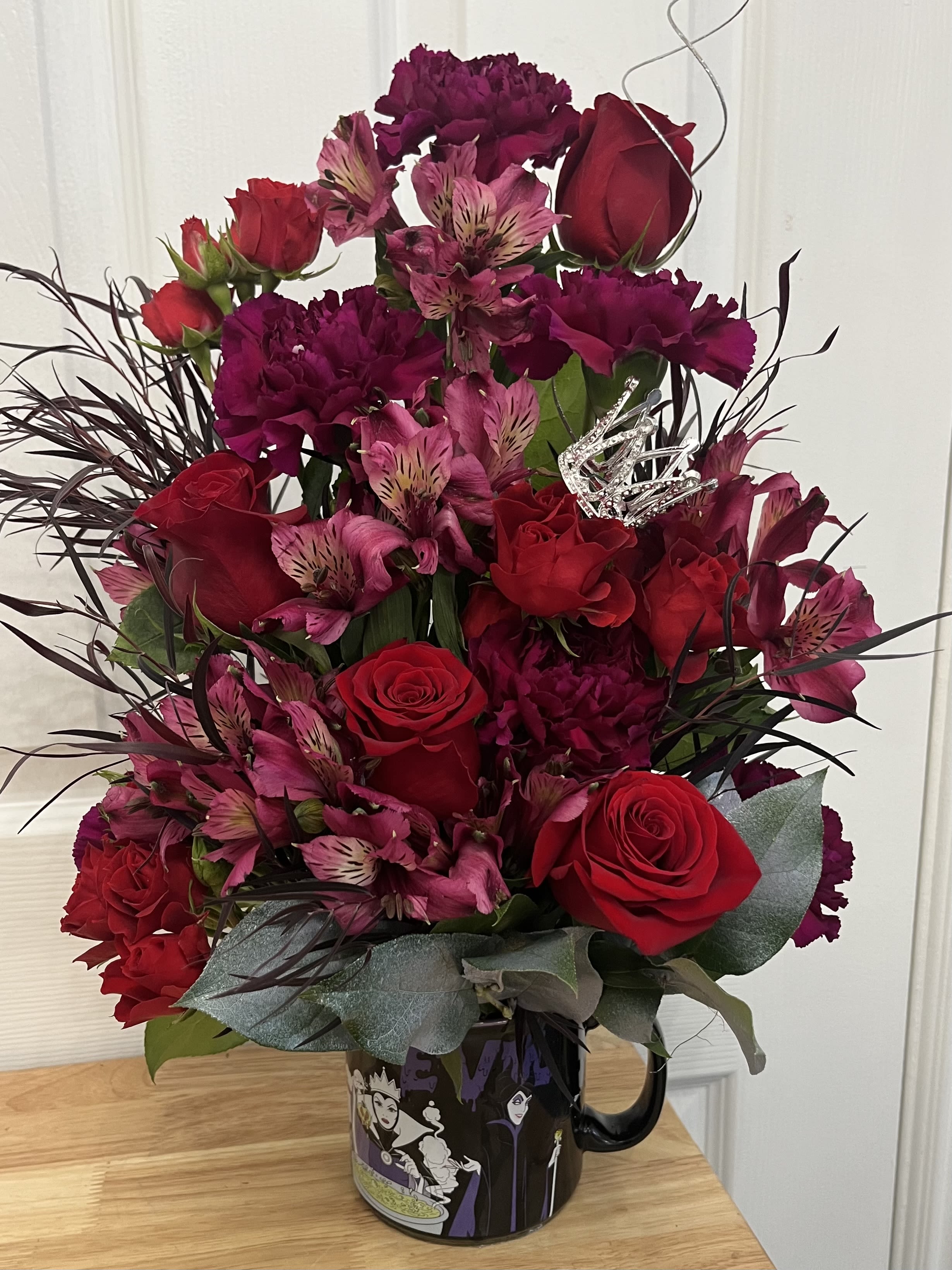 Red roses and pink alstroemeria in a black mug with decorative picks