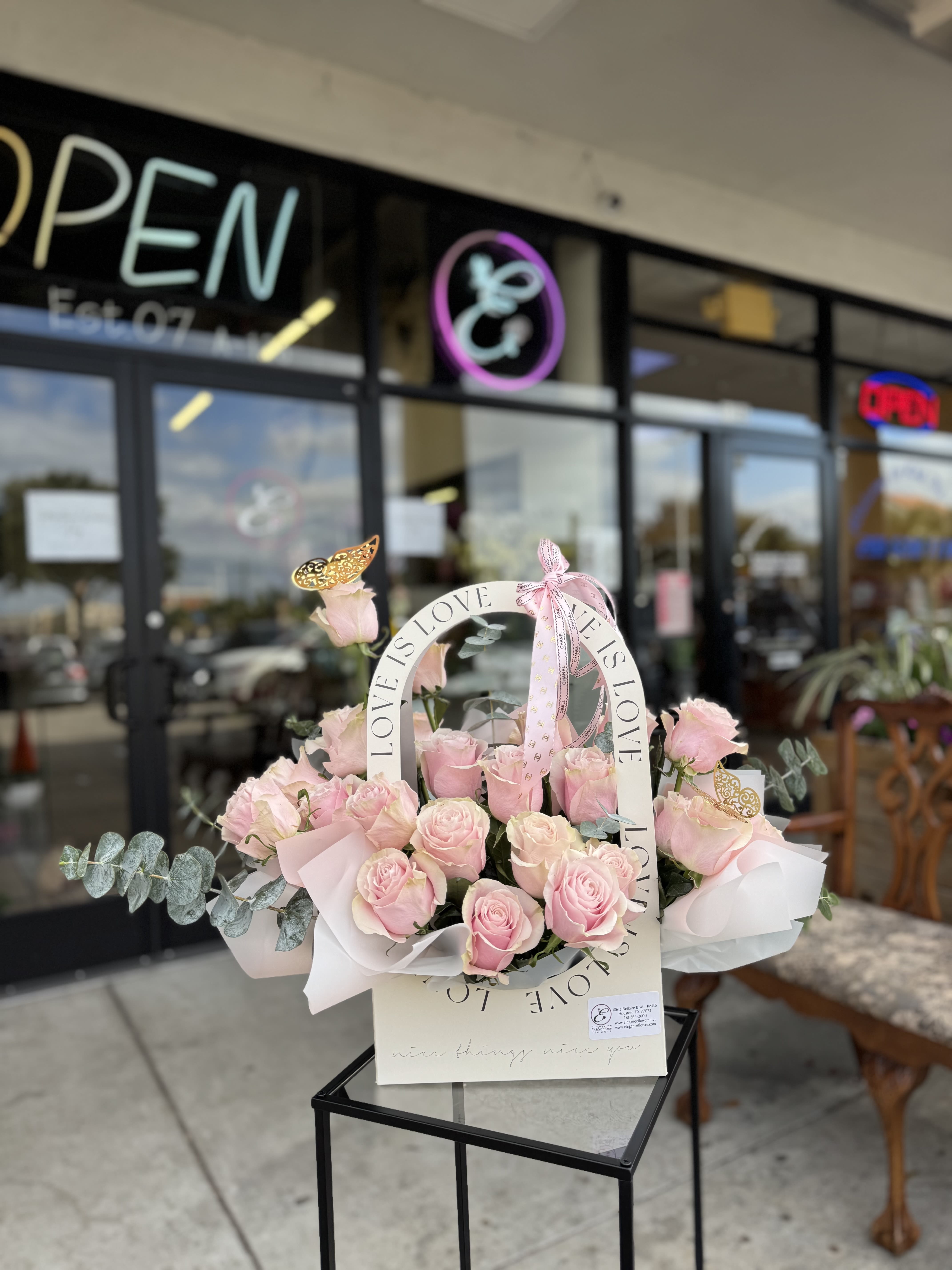 Pink roses arranged in a white basket with a LOVE ribbon