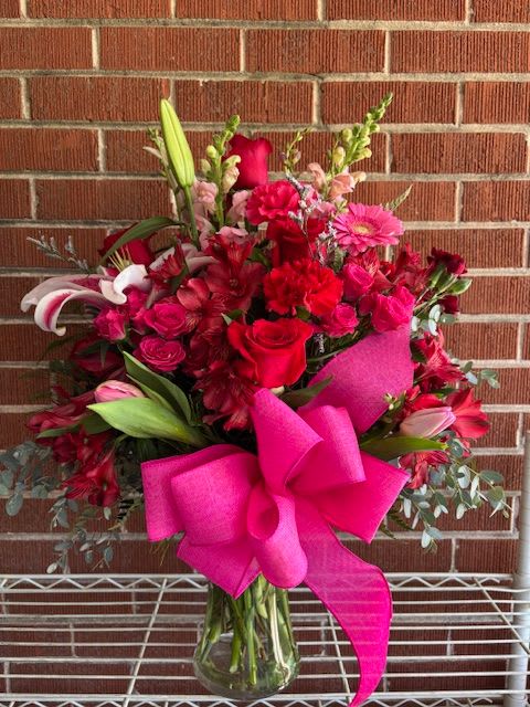 Simply Smashing - This romantic array of roses, lillies, gerber daisies, carnations, mini carnations, larkspur, snap dragons, alstroemerias, and mixed greens in a smashing ruby red vase. Simply Smashing!