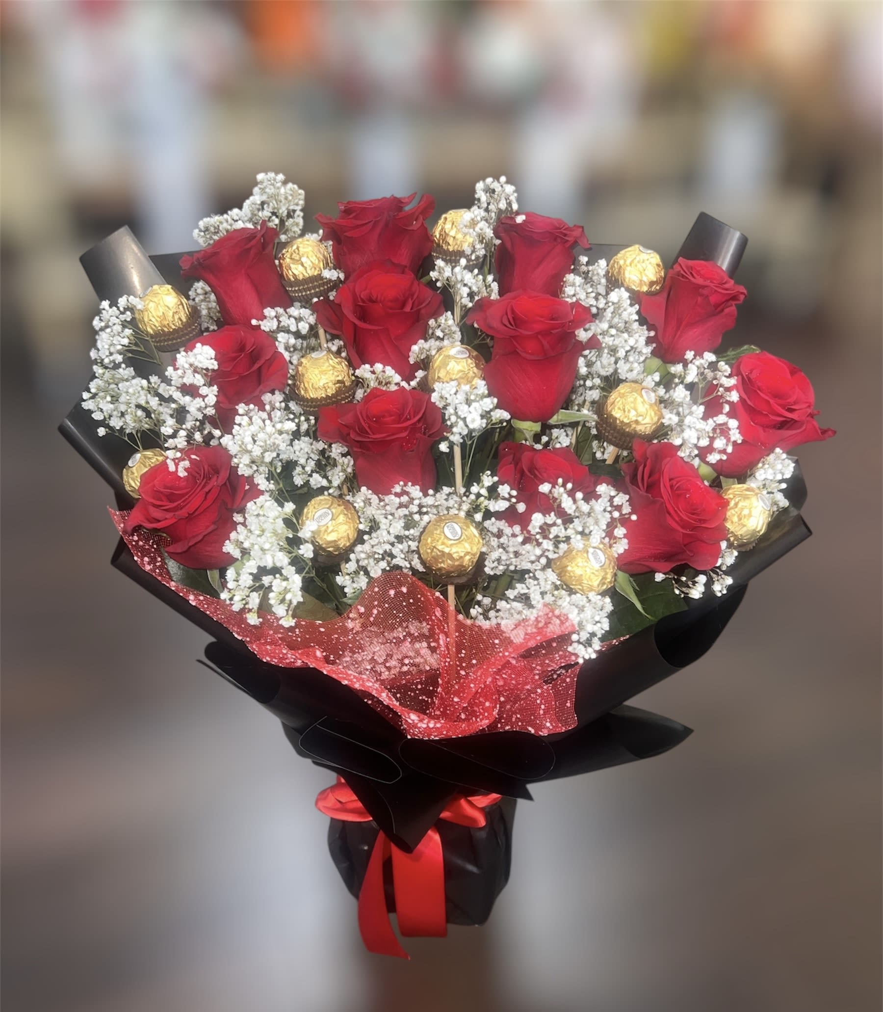 Bouquet of red roses with gold-wrapped chocolates and white baby's breath