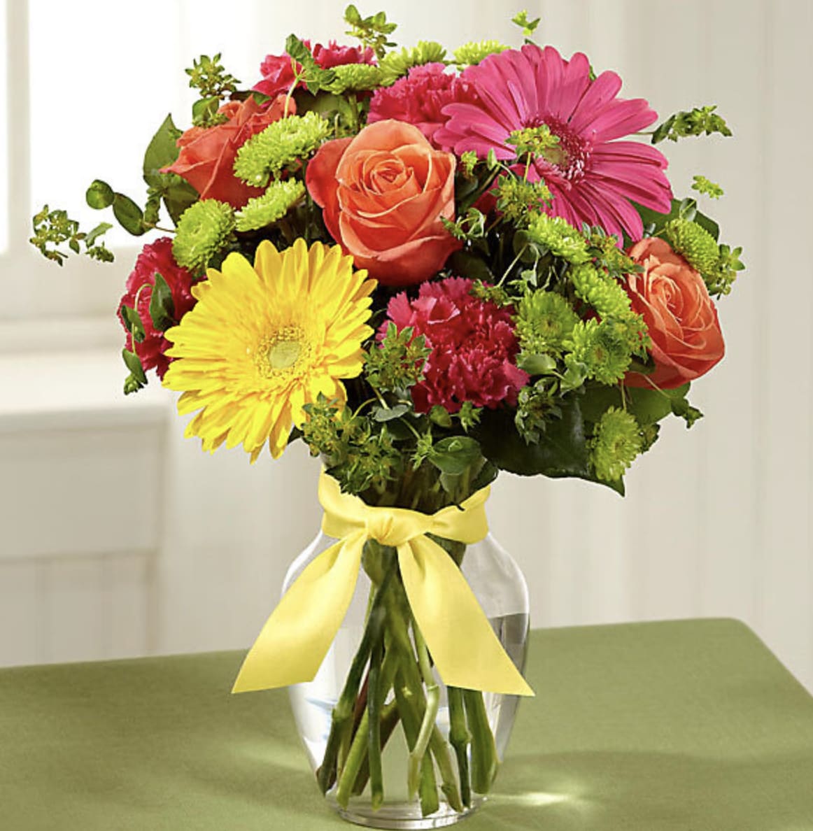 Mixed bouquet of roses, gerbera daisies, and carnations in a glass vase