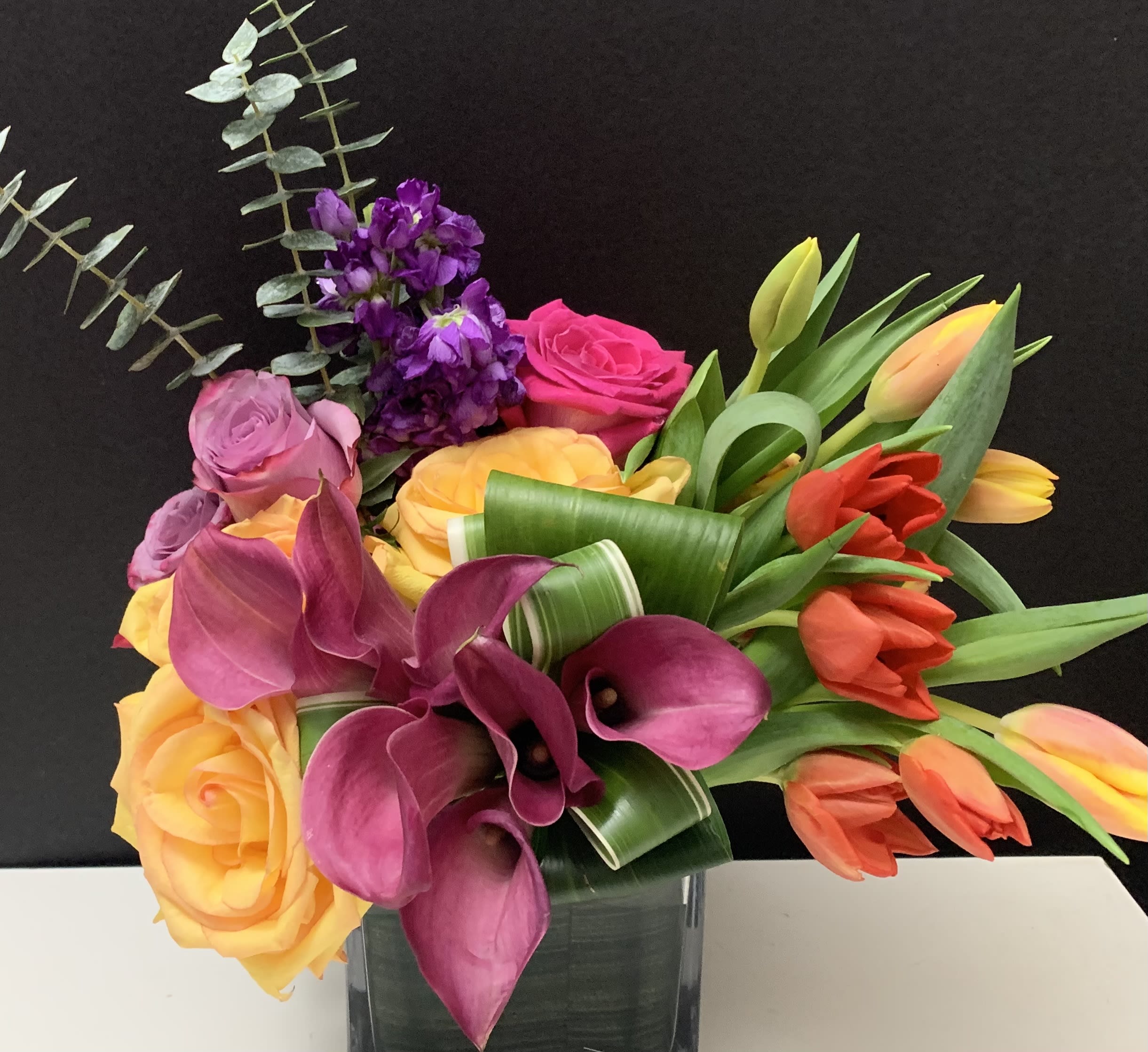 Bouquet of roses, calla lilies, and tulips in a glass vase