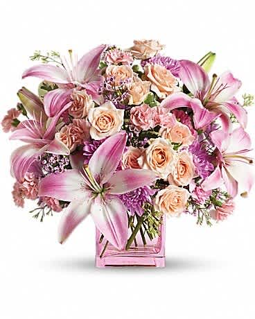 Pink lilies and peach roses arranged in a pink glass vase