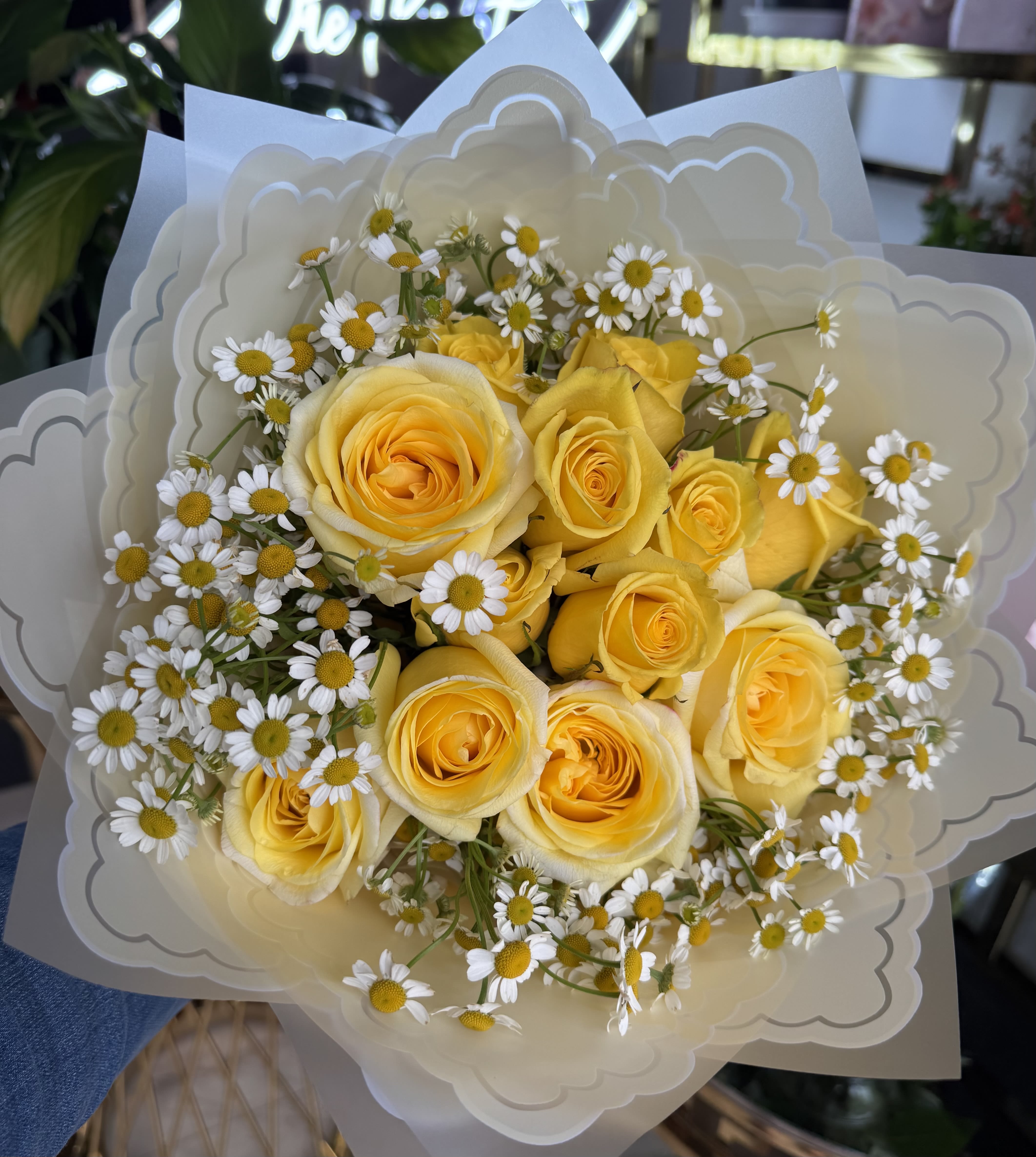 Bouquet of yellow roses and small white daisies wrapped in cream paper