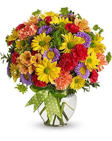 Colorful mixed bouquet in a clear glass vase with a green polka-dot ribbon