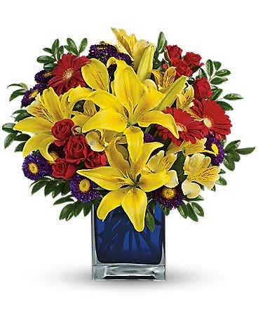 Bouquet of yellow lilies, red roses, and purple daisies in a blue glass vase