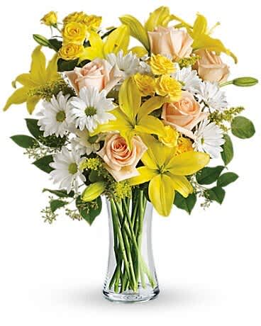Bouquet of yellow lilies, peach roses, and white daisies in a clear glass vase