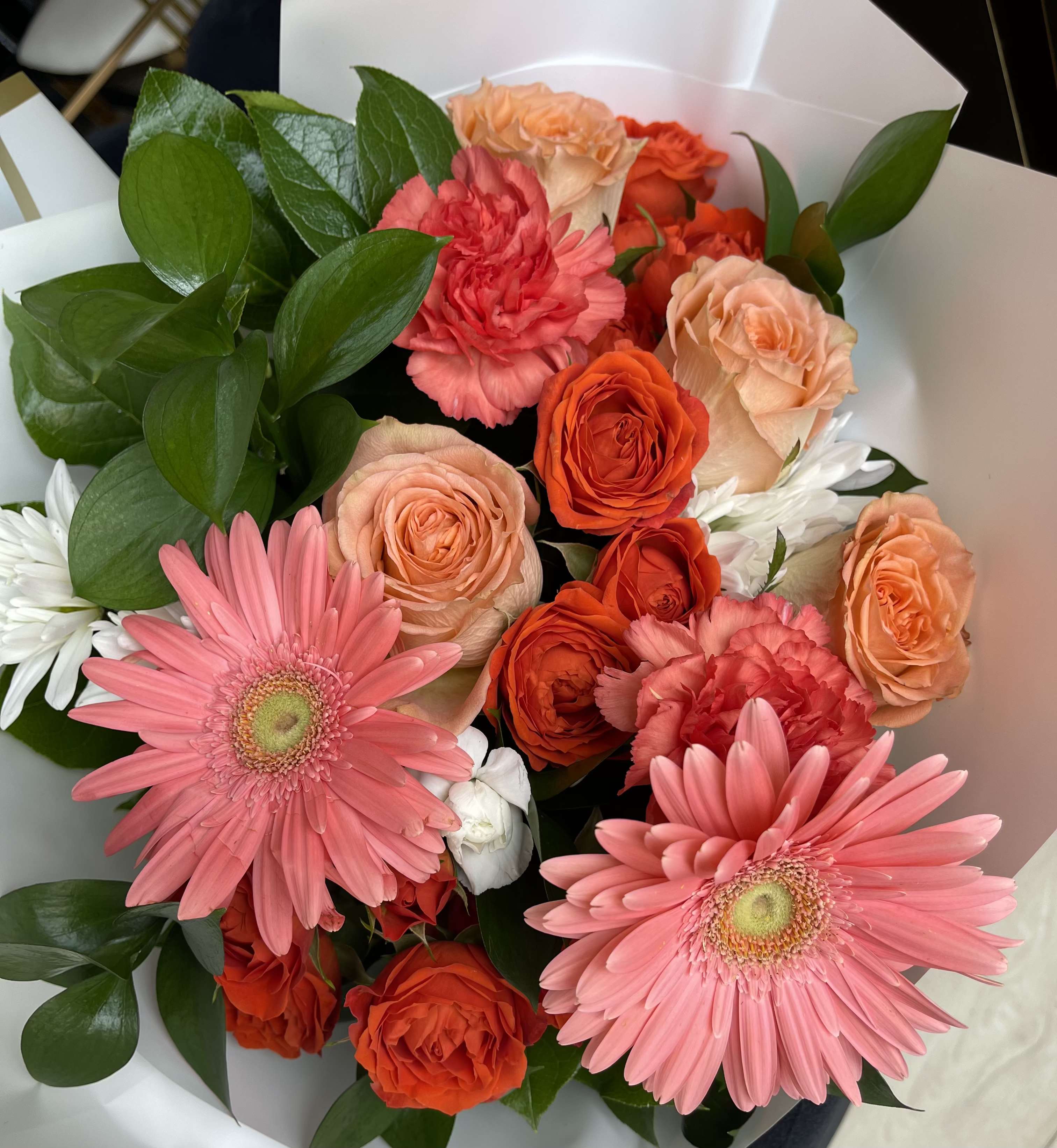 Bouquet of pink gerbera daisies, orange roses, and carnations with white daisies