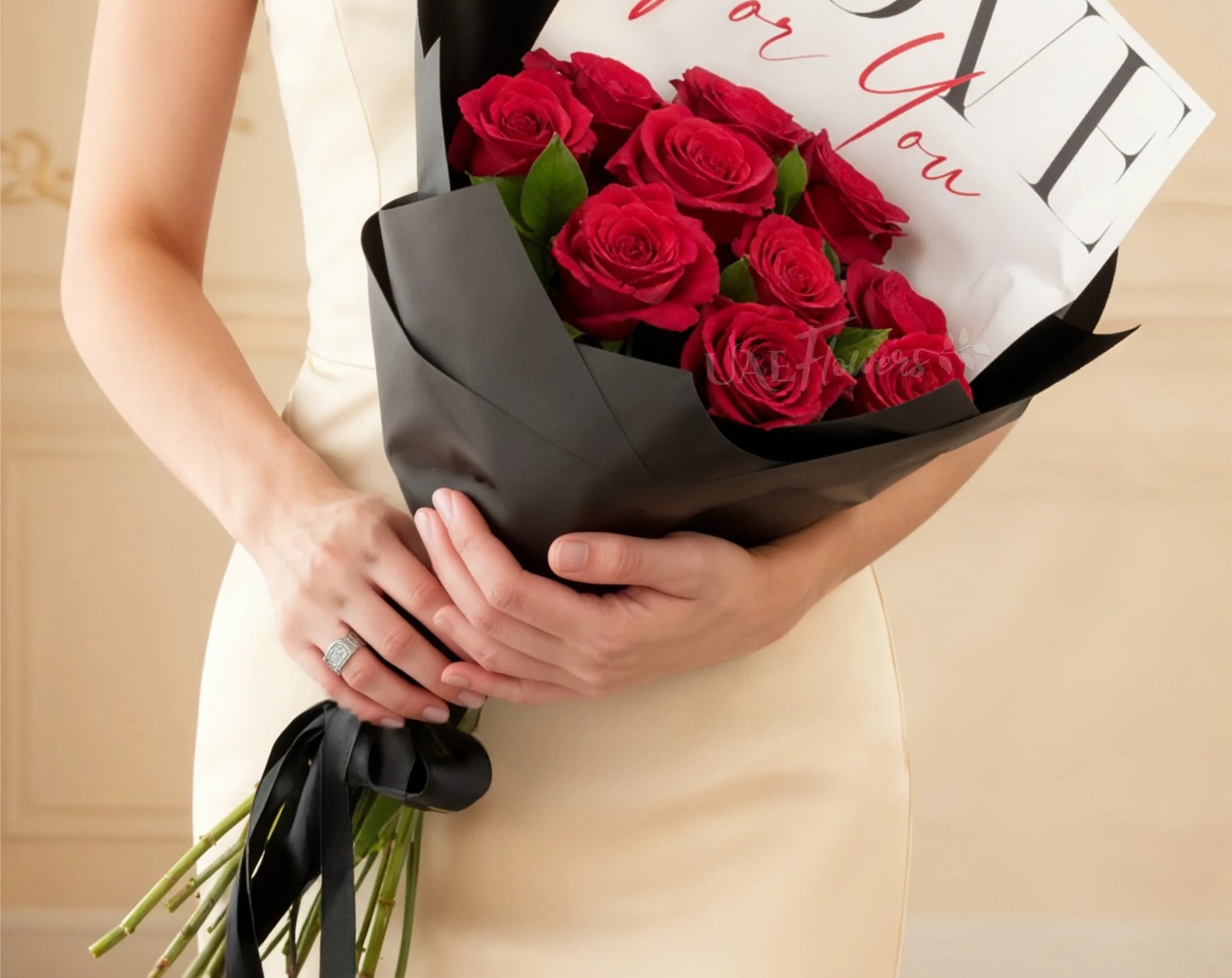 Woman holding a bouquet of red roses wrapped in black paper