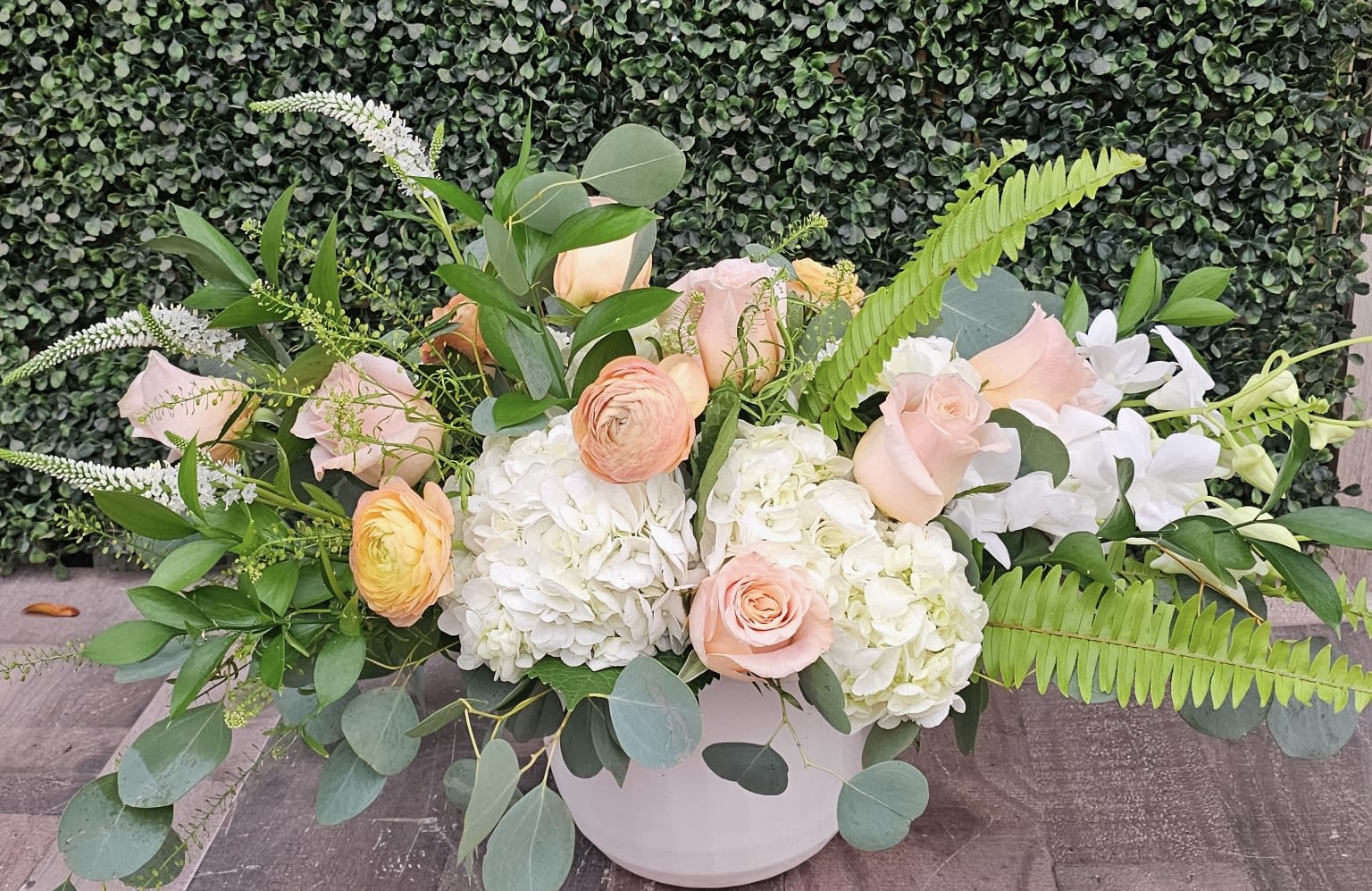 PEACHES - A colorful peach and white arrangement with greens in a container. 