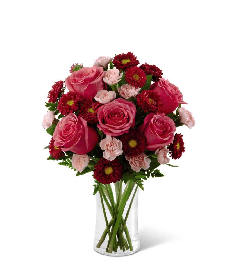 Pink roses and red daisies arranged in a clear glass vase
