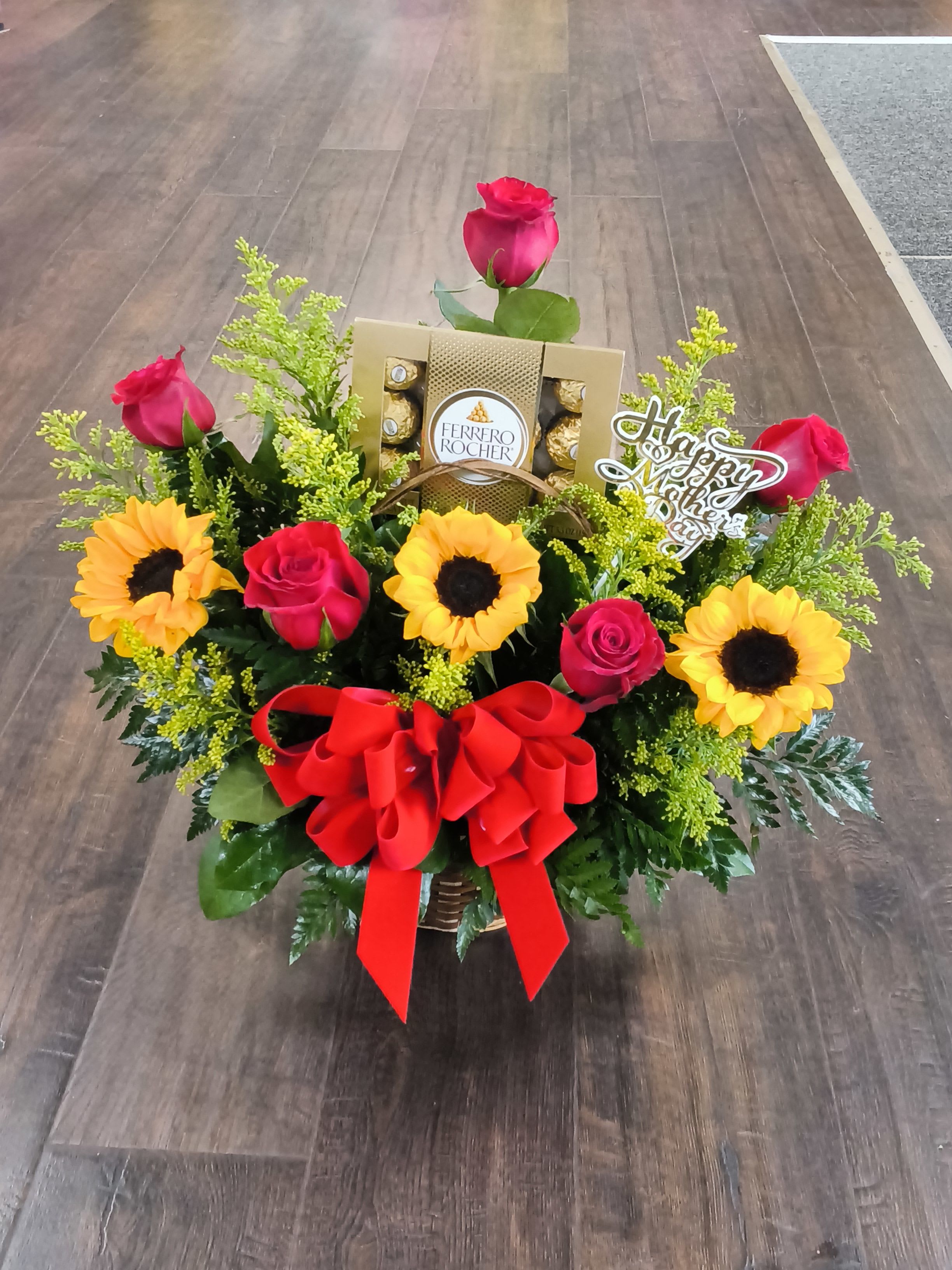 Sunshine - A bright and joyful arrangement featuring sunflower, red roses, fresh greenery, and Ferrero Rocher chocolates, finished with a bold red bow. The perfect gift to make Mom smile.