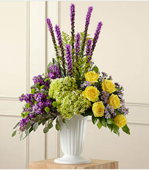 Purple and yellow floral arrangement in a white vase