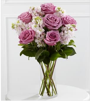 Pink roses with white filler flowers in a clear glass vase