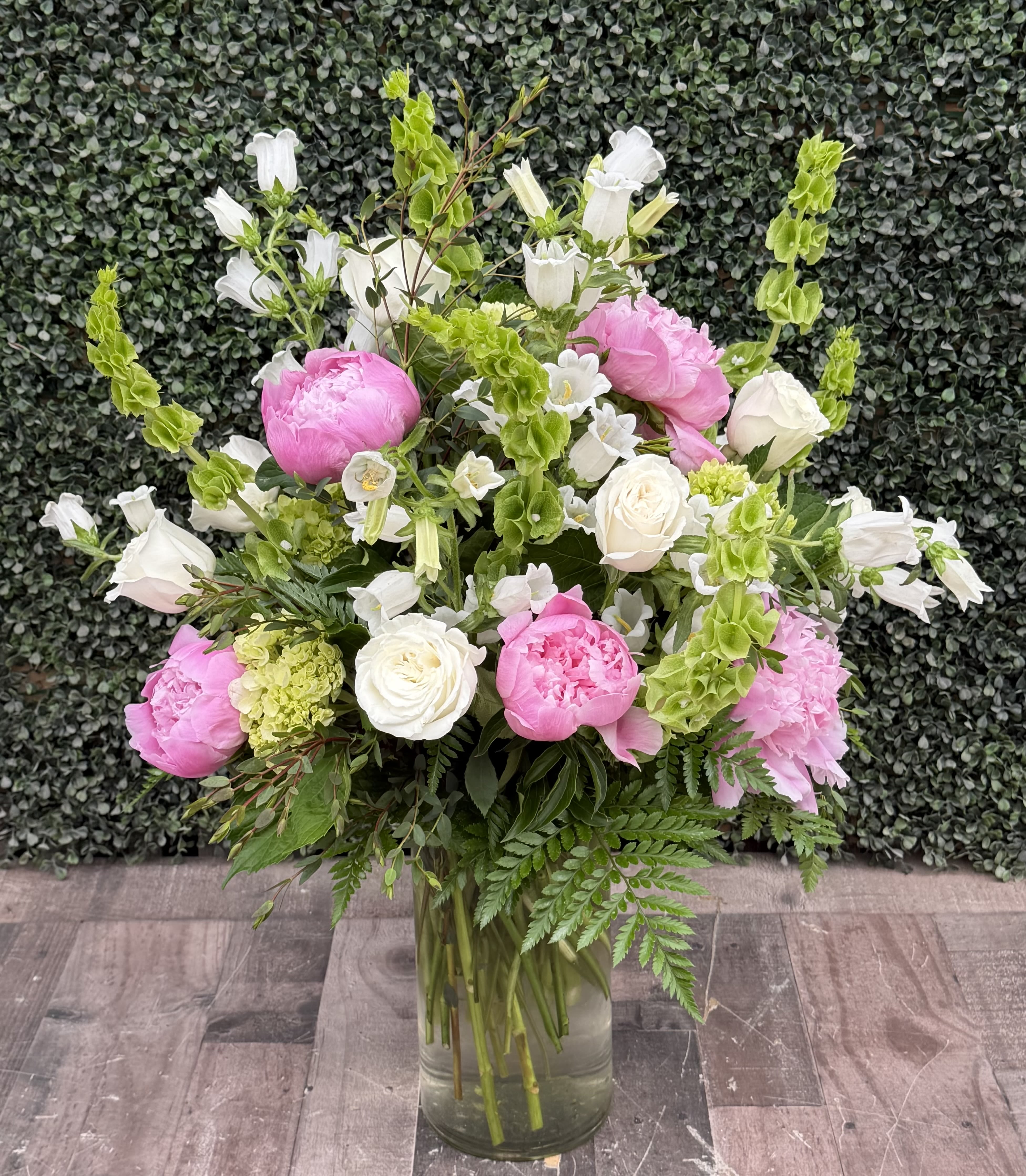 DREAM GARDEN - This classic arrangements come designed with pink peonies, white roses, hydrangeas, campanella, bells of Ireland and more. 