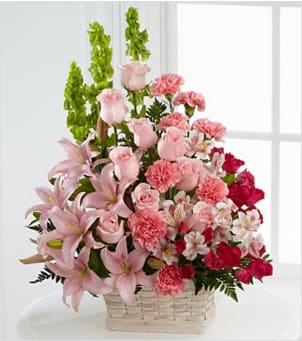 Pink lilies, roses, and carnations in a woven basket