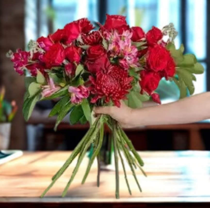 Bouquet of red roses and pink flowers being held by hand