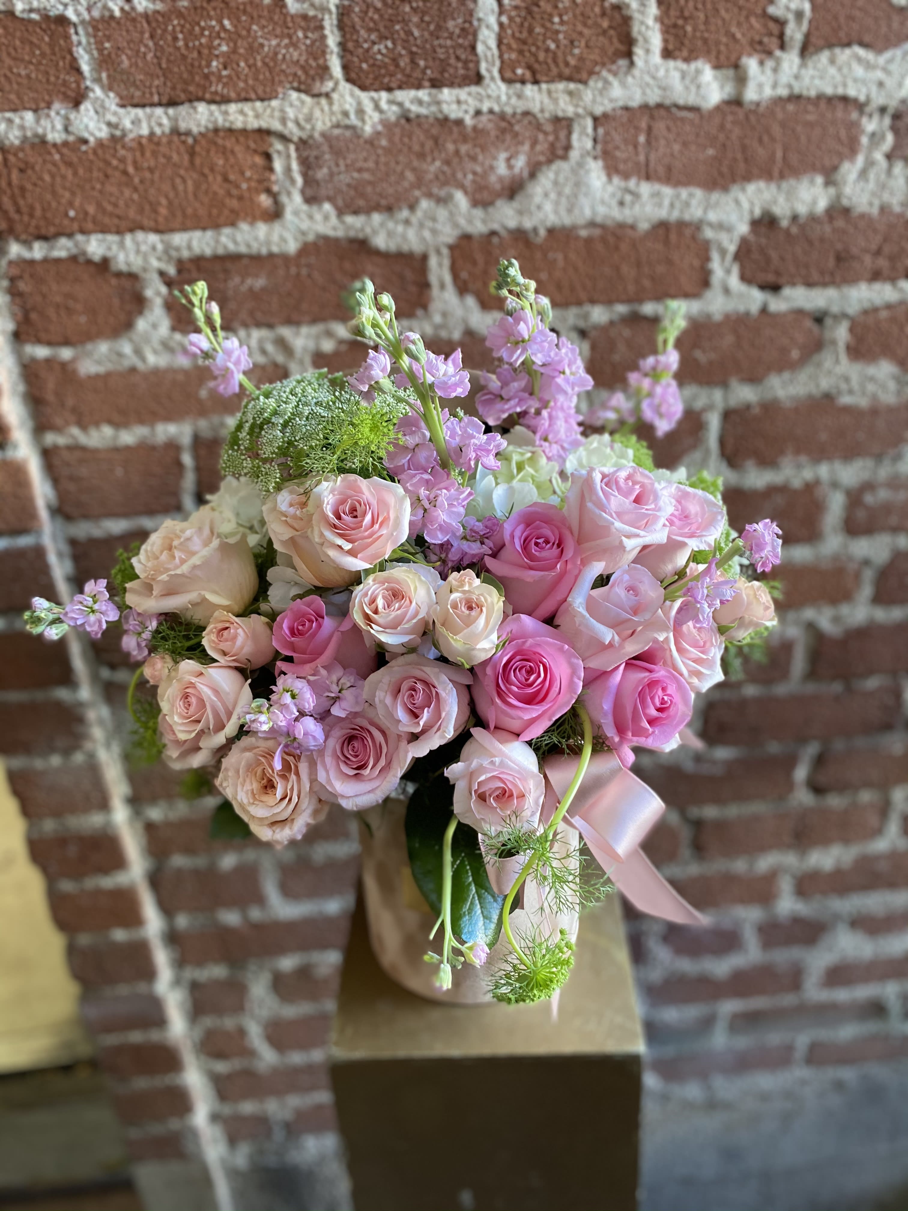 Pink and blush roses arranged in a round bouquet with a pink ribbon