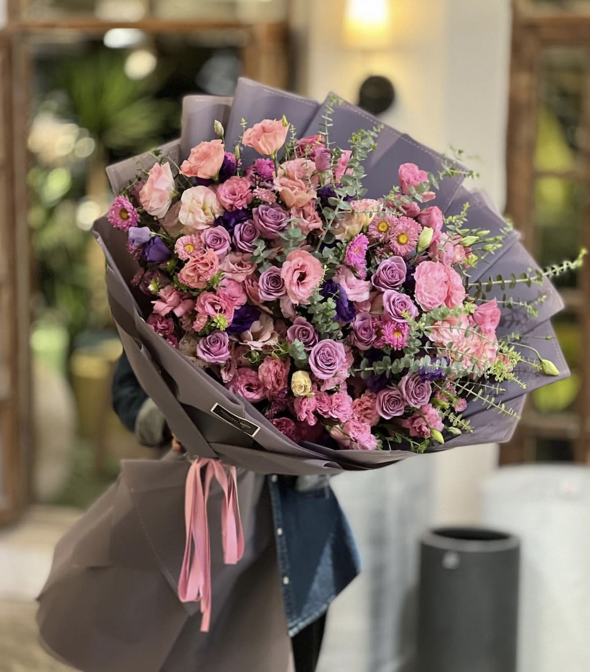 Large bouquet of pink and purple roses wrapped in lavender paper