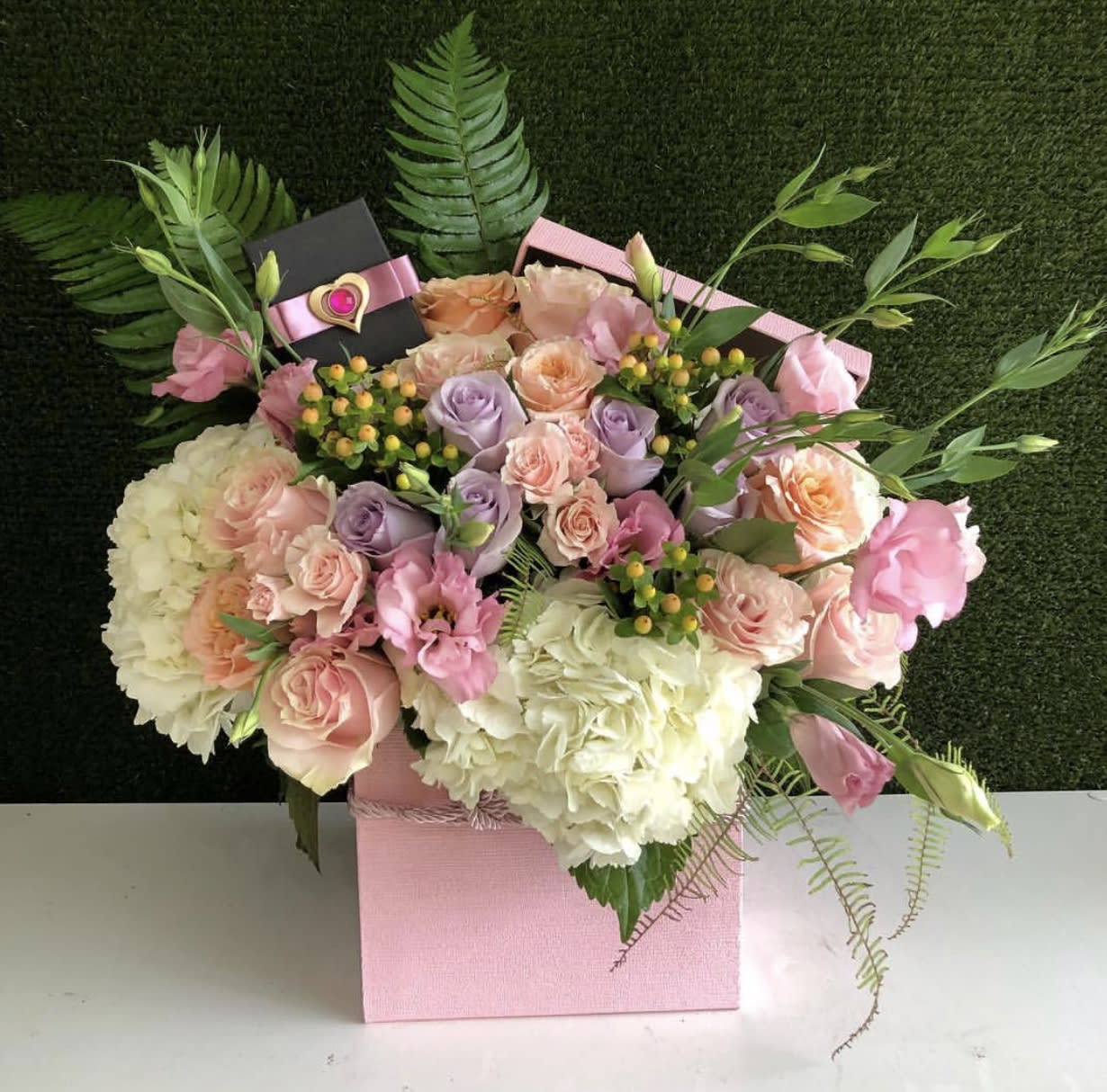 Pink and lavender rose bouquet in a pink gift box with a ribboned card