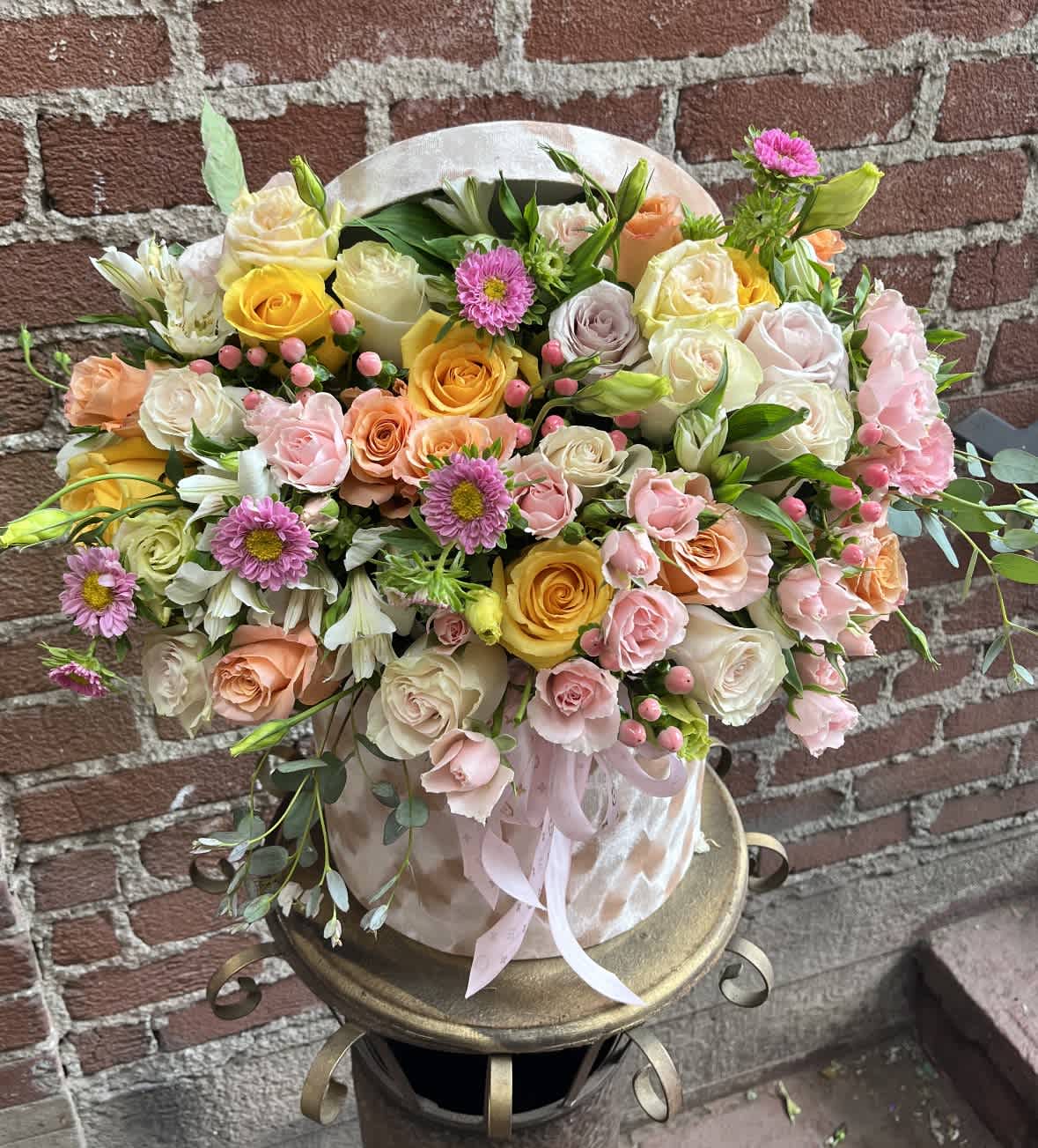 Mixed bouquet of roses and pink daisies in a round hatbox