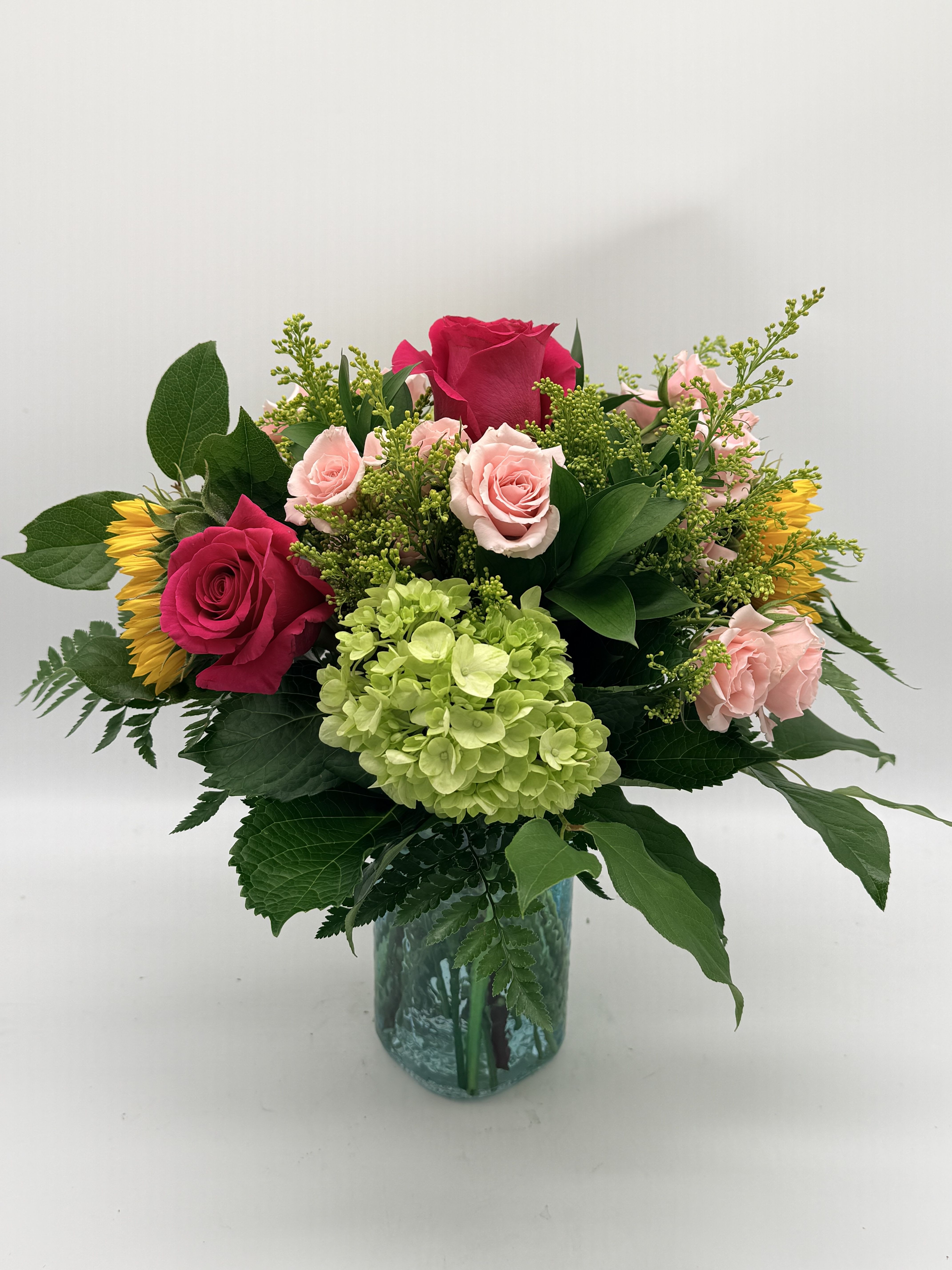 Springtime Love - Bursting with color and freshness, this arrangement brings together vibrant roses, cheerful sunflowers and seasonal blooms arranged in a blue mason jar. It's a bright and beautiful way to celebrate Mom with the essence of spring in every stem.