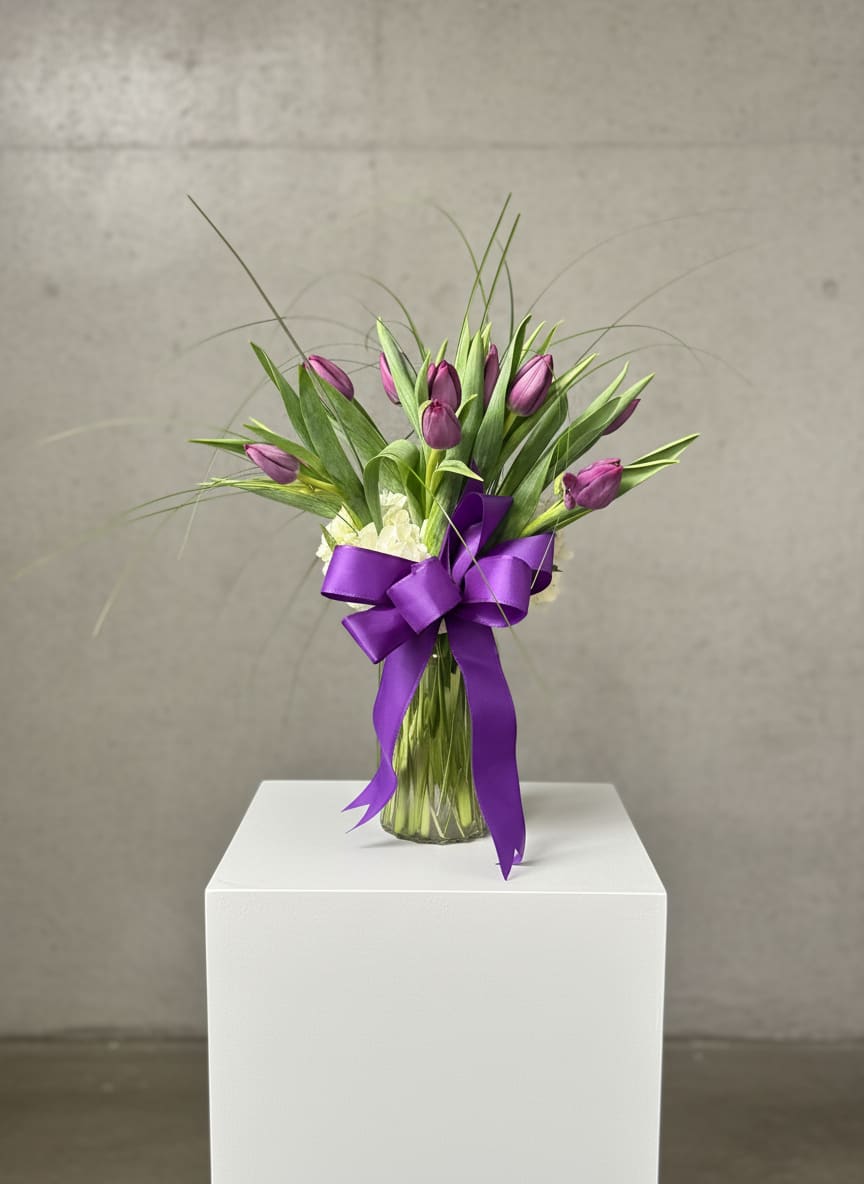 Passionate Purple Tulips - For anyone who's passionate about purple, this majestic arrangement of the prettiest purple tulips.  Spring's loveliest and most vibrant purple tulips (shade of purple/ lavender may vary) with a base of white hydrangea are delivered in a vase that's wrapped up with a purple ribbon.  Approximately 12 1/2" W x 14 3/4" H  Orientation: All-Around  Standard: 10 Tulips Deluxe: 20 Tulips Premium: 30 Tulips